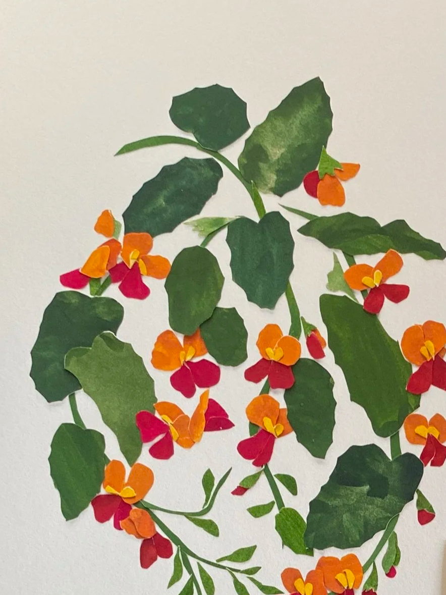 Paper collage of green leaves and orange and red flowers arranged on a white background