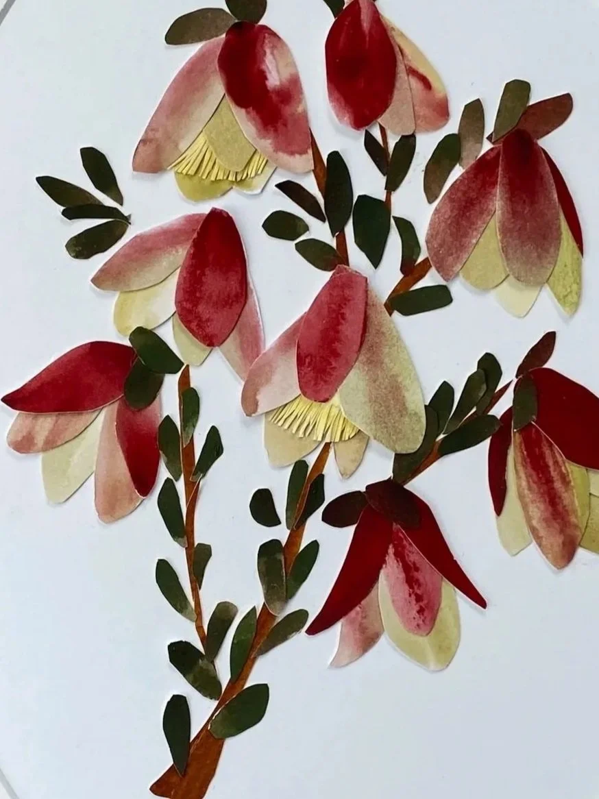 A collage of cut-out paper leaves and flowers arranged on a white background, with red, pink, yellow, green, and brown colors of qualup bell flower.