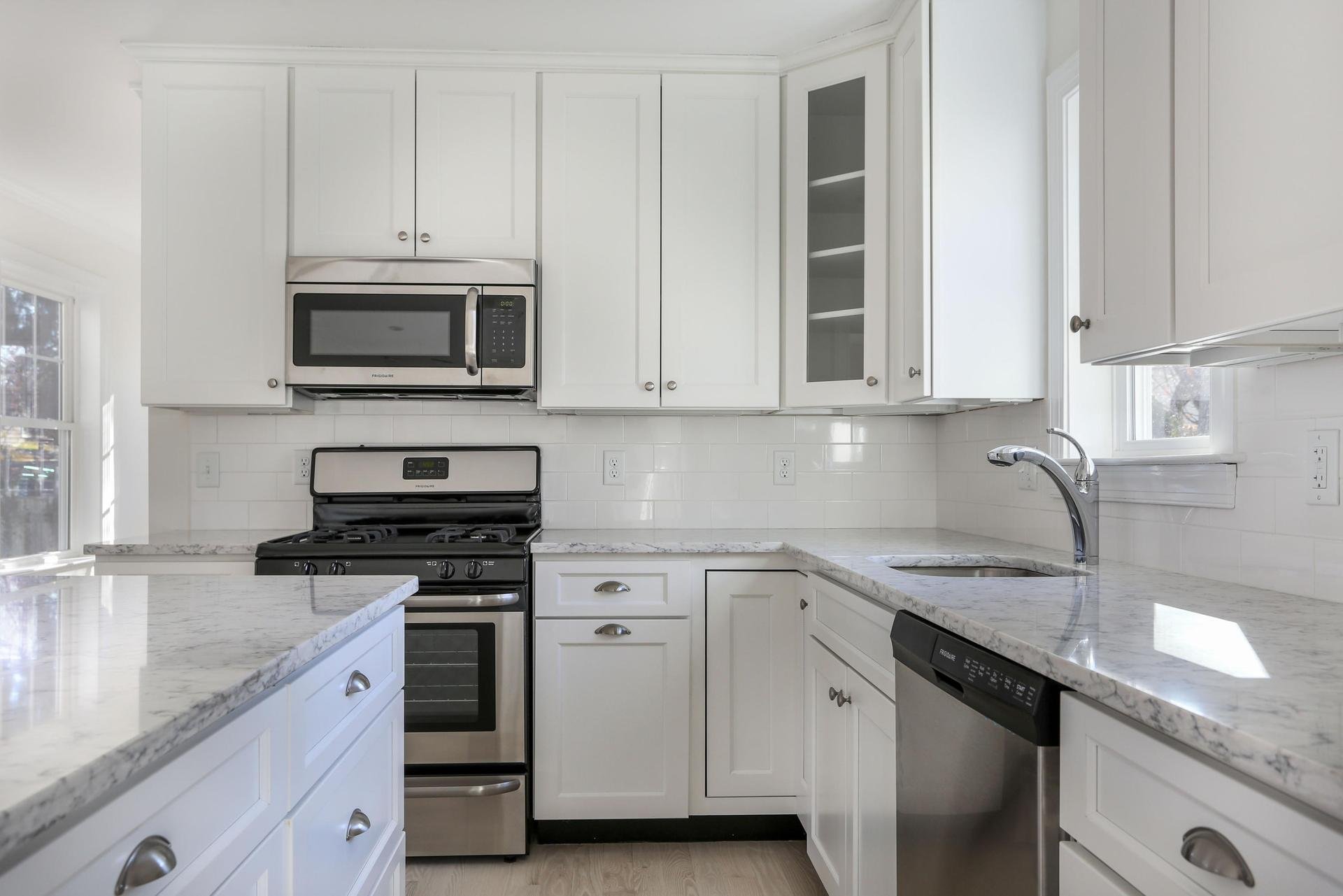 Stainless steel appliances and silver hardware in white kitchen.jpeg