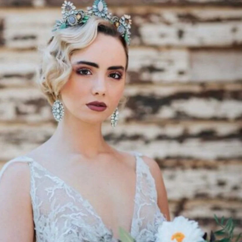 Woman with vintage-inspired bridal hairstyle, polished makeup and statement headpiece in an elegant wedding beauty look.