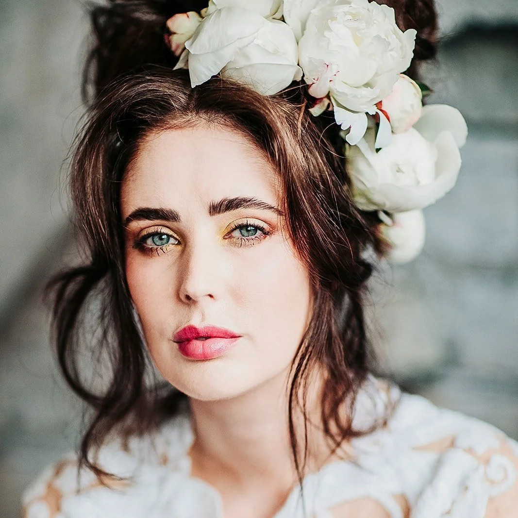 Woman with soft makeup, pink lips and a floral hairstyle creating a complete elegant beauty look.