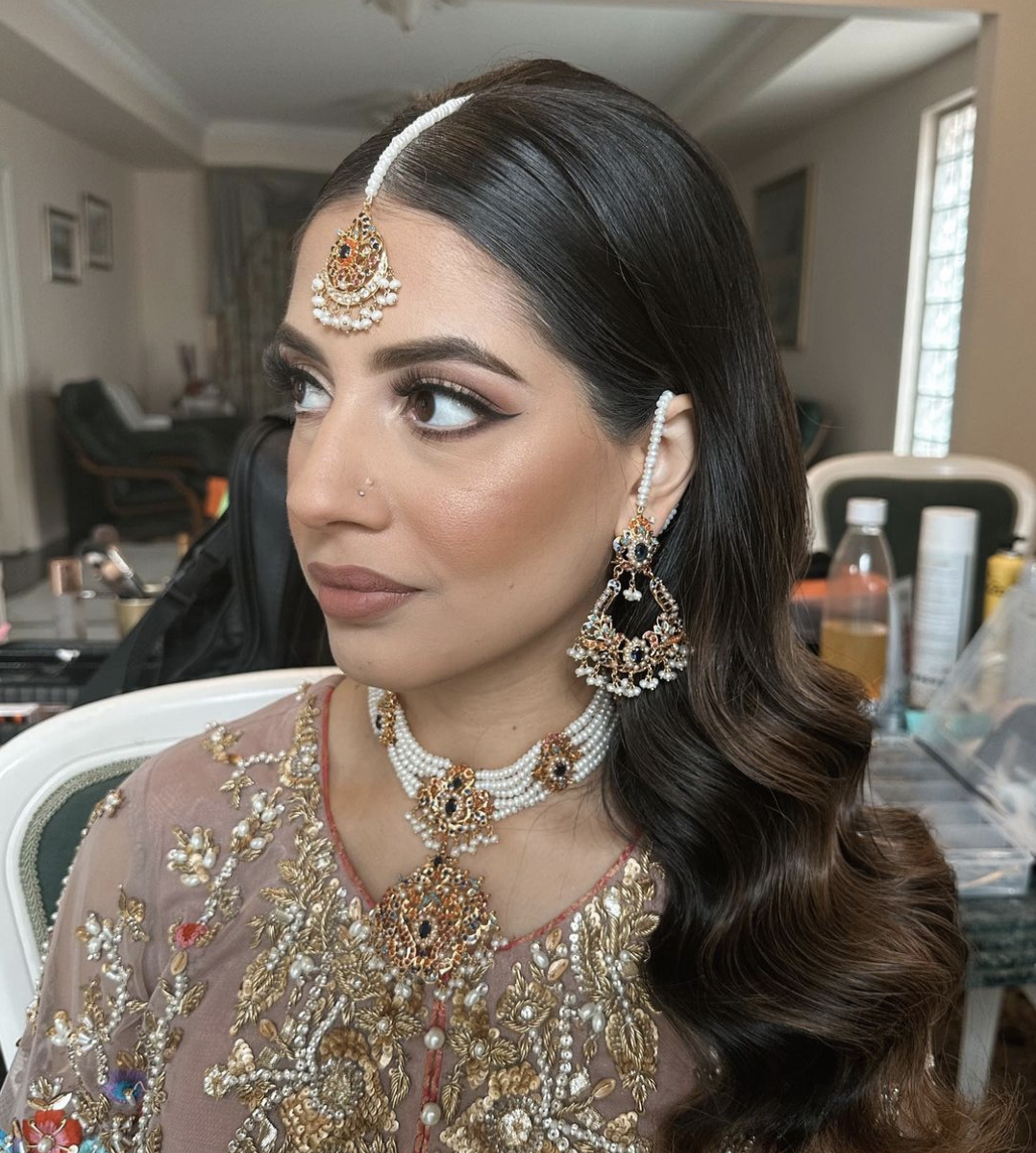 Indian bride with long black hair in smooth waves with tikka wearing traditional wedding dress and bridal makeup