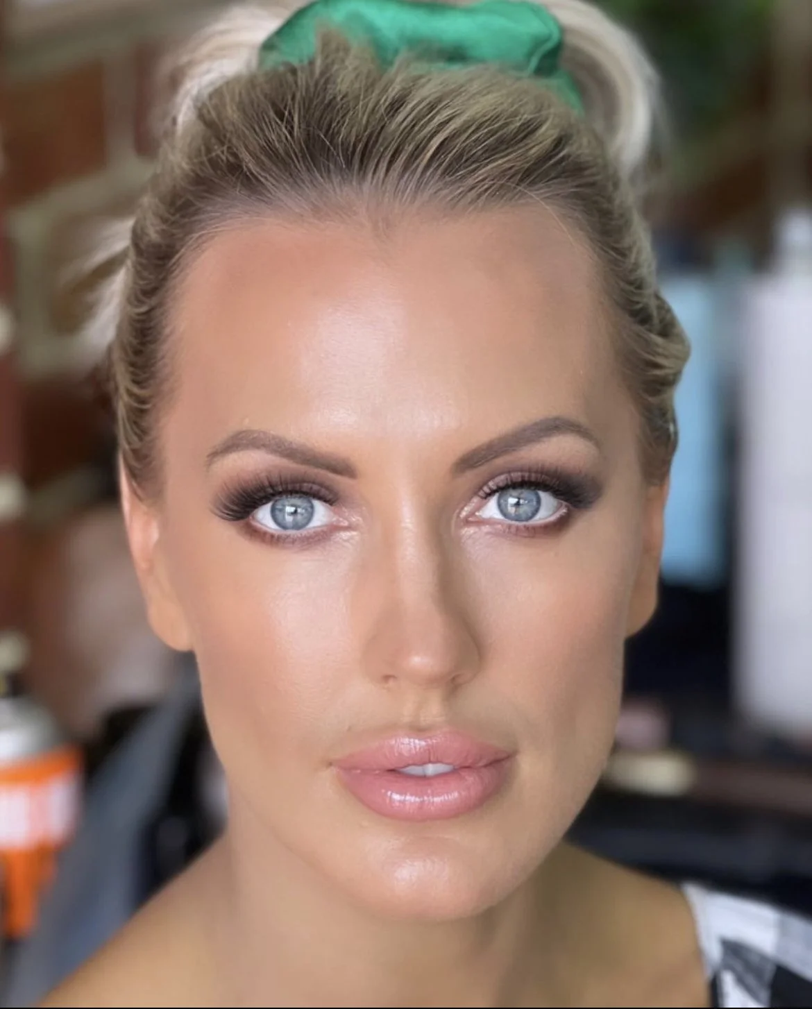 Close up of bridal makeup, blonde girl with hair up, blue eyes, glossy dewy skin, smokey eye makeup
