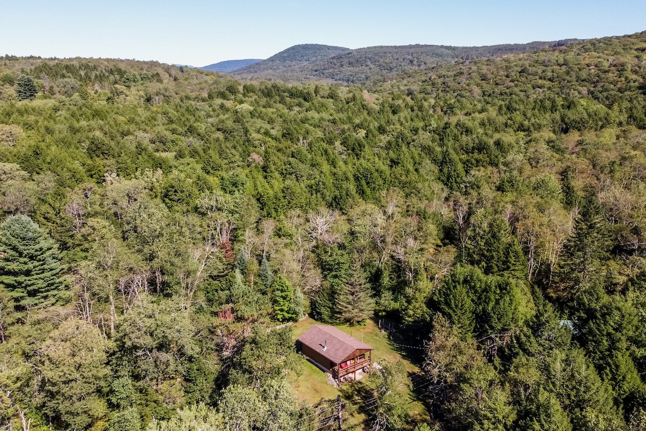 Classic Catskills log cabin with wood stove on a quiet historic road in