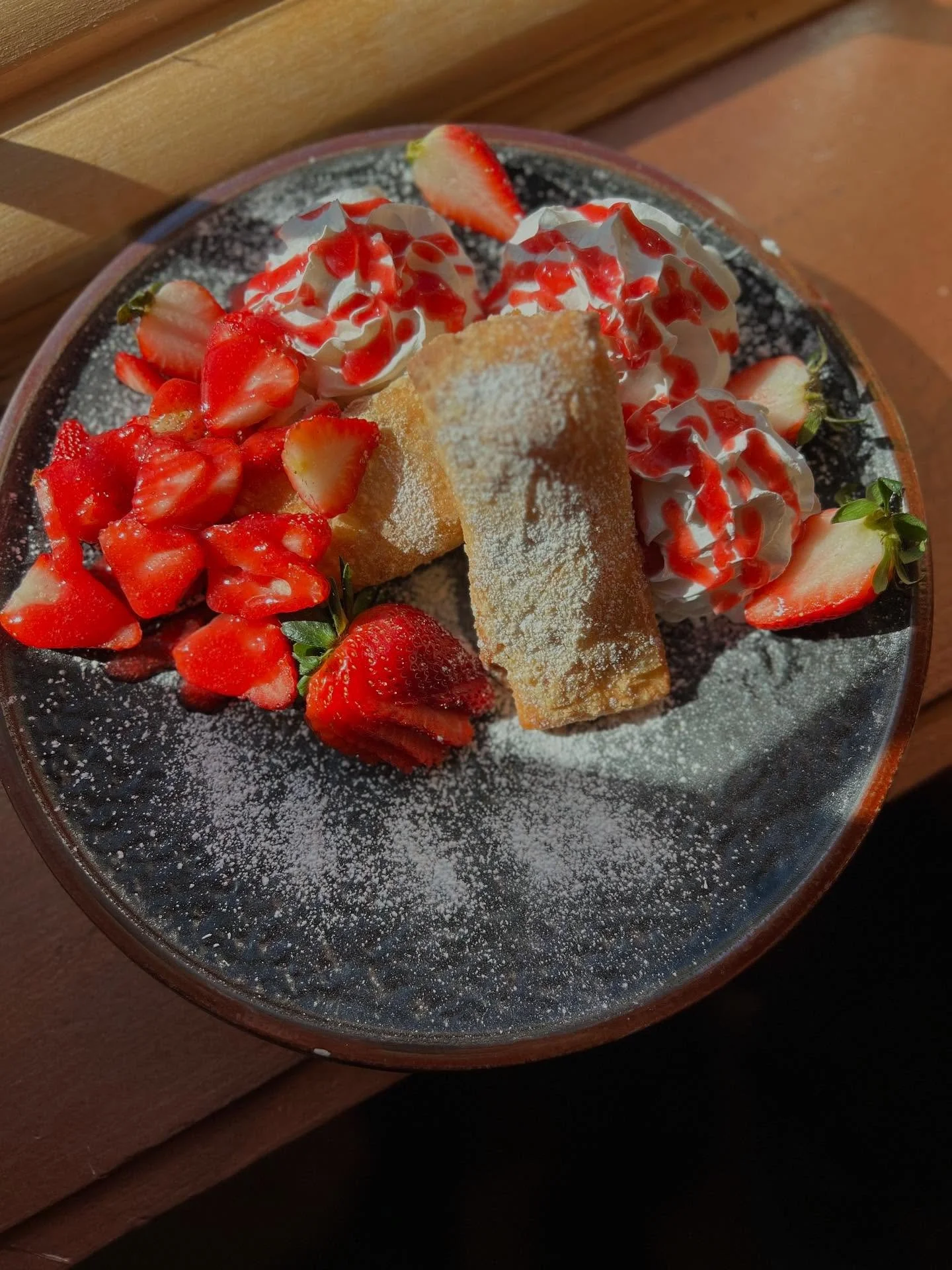 Strawberry Lindbergh - Cream cheese filled spring rolls, topped with fresh strawberry sauce finished with powdered sugar, strawberries and whipped cream