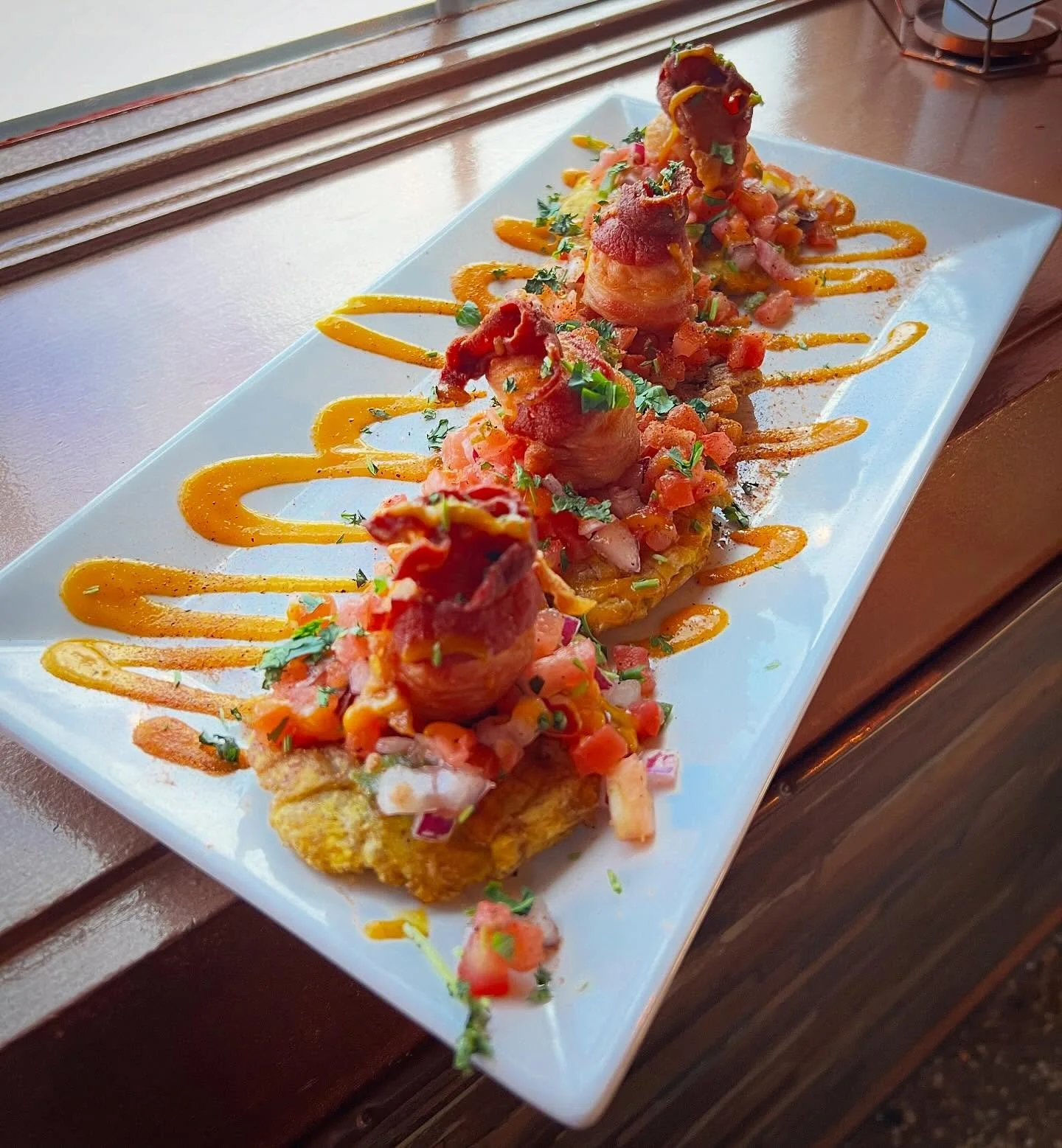 Scallop &amp; Tostones- bacon wrapped scallops seared with Cajun spices. Served over house made Pico De Gallo and fried green plantains