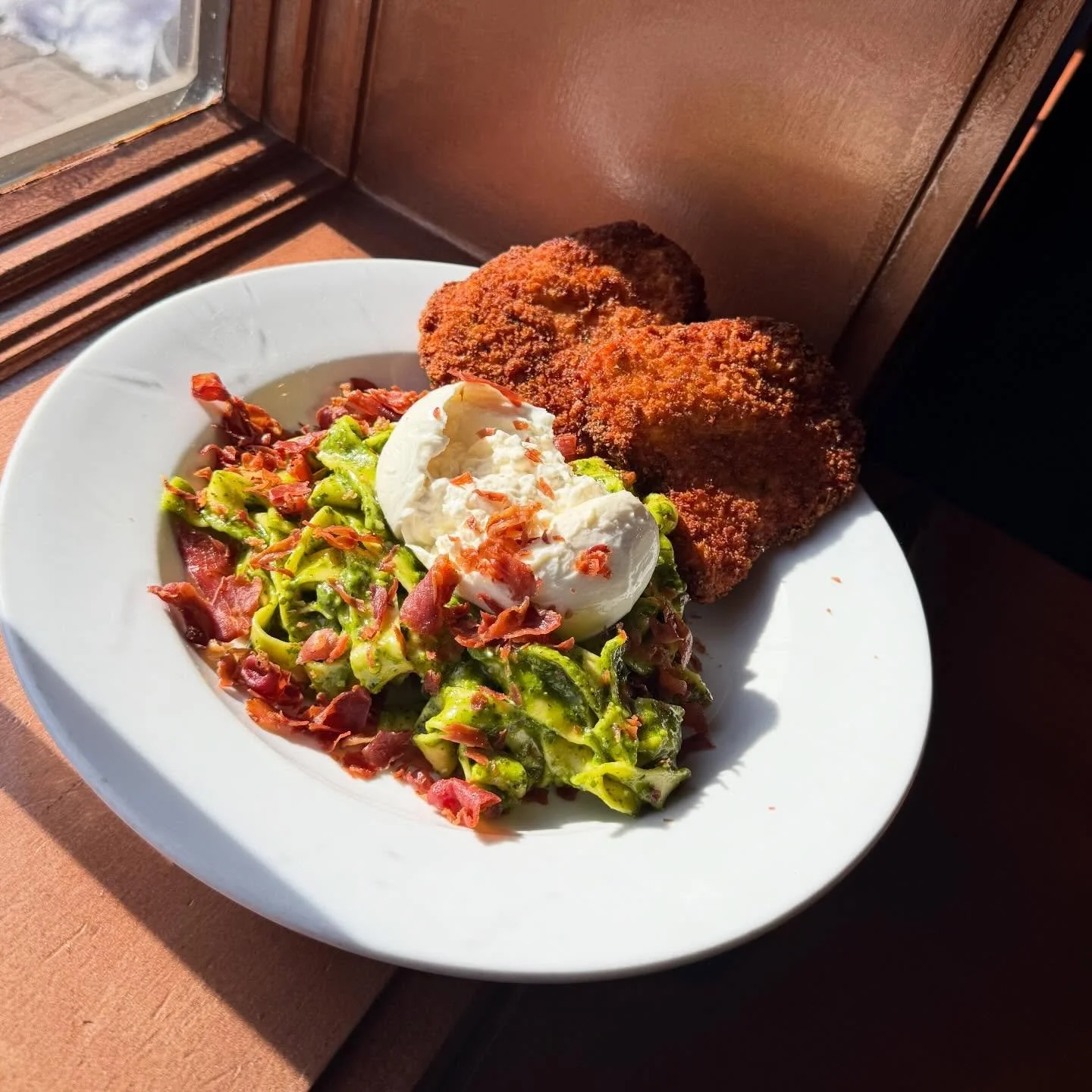 Pesto Pappardelle- Pappardelle pasta tossed with house made pistachio pesto, topped with whole burrata, panko chicken and finished with crispy prosciutto