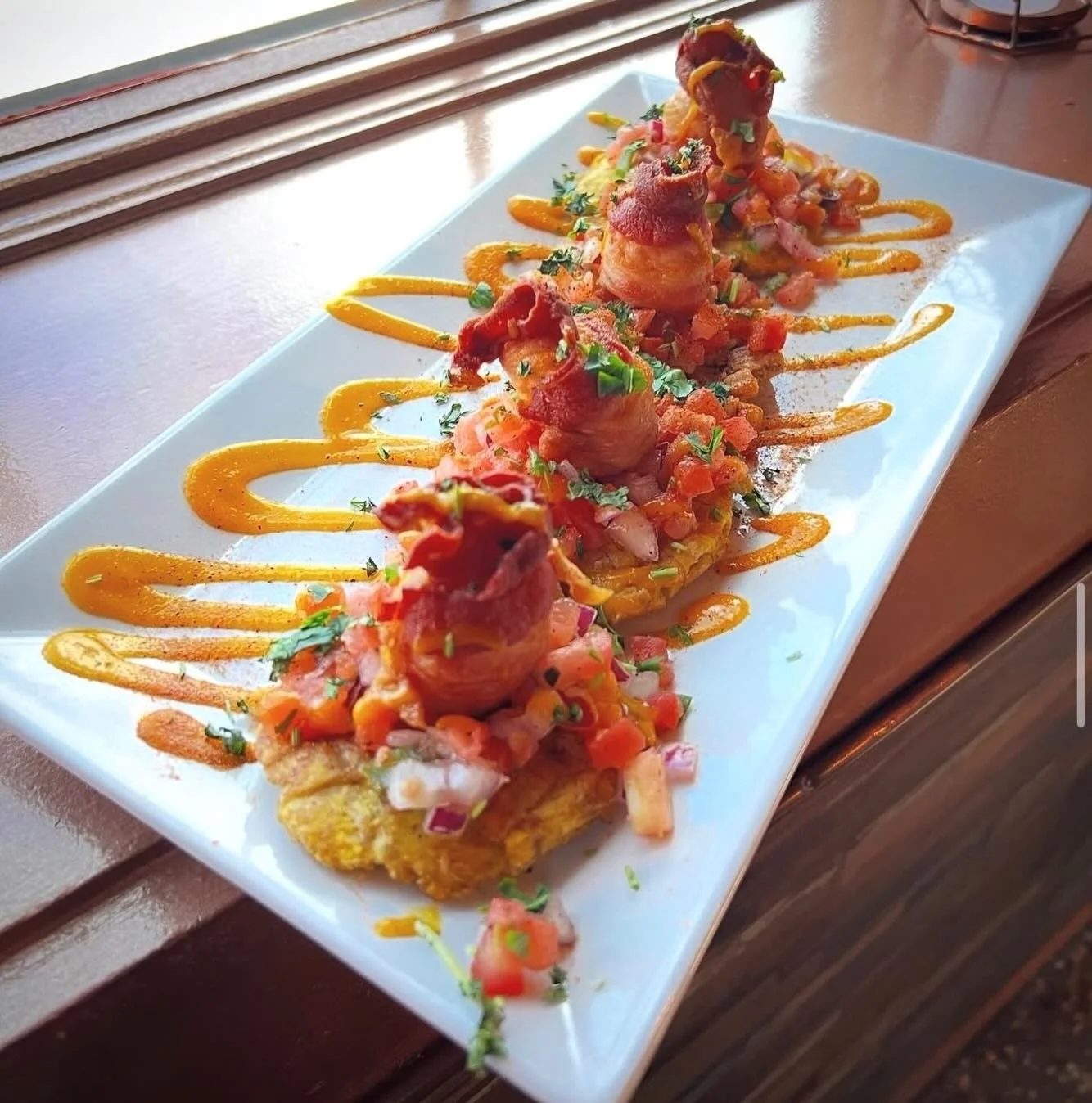 Scallop &amp; Tostones- bacon wrapped scallops seared with Cajun spices. Served over house made Pico De Gallo and fried green plantains