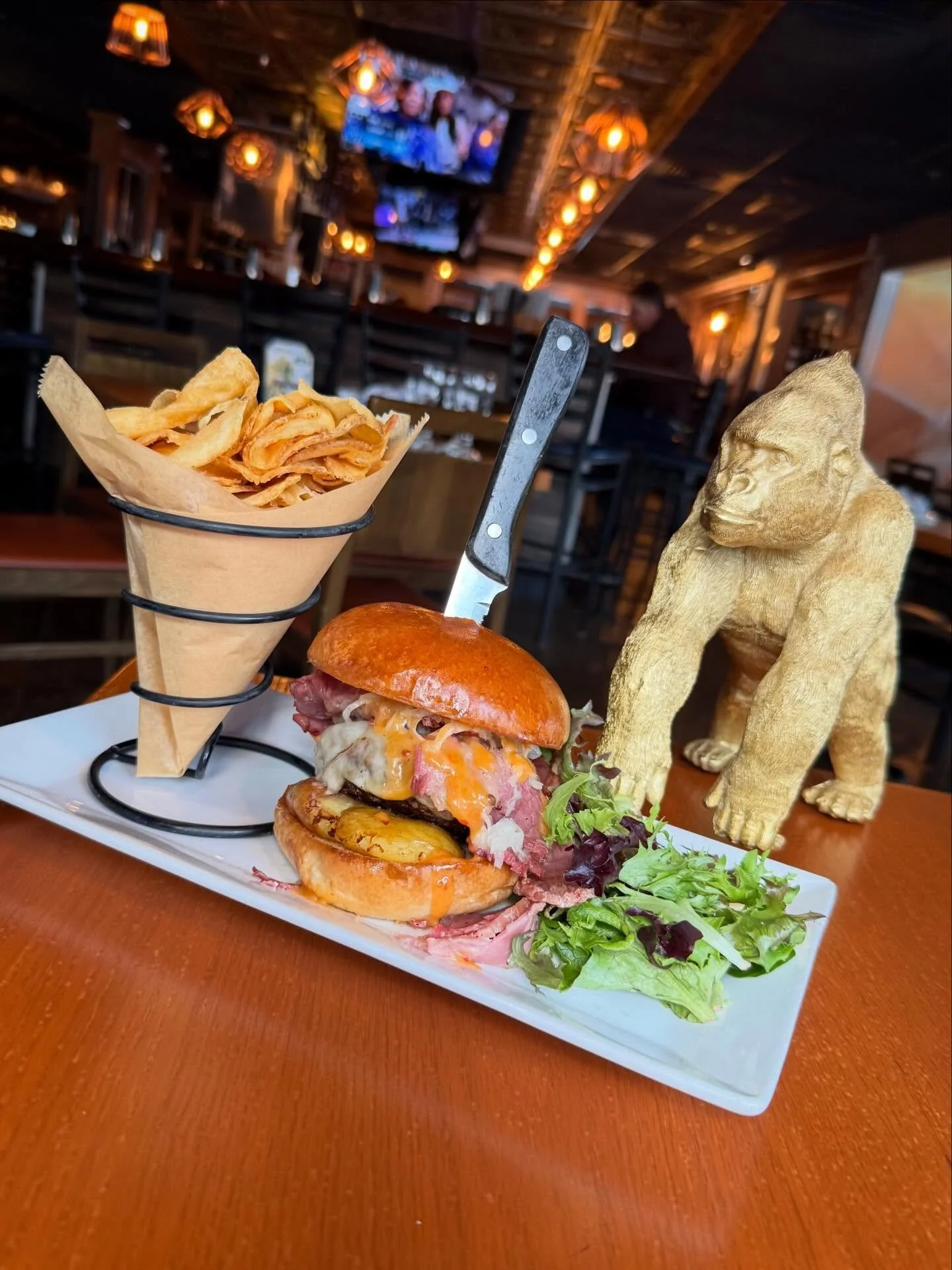 Lucky Monkey Burger- Half pound hand pressed angus beef topped with melted Swiss cheese, stacked with sliced corned beef, crispy smashed potato, and tangy sauerkraut. Finished with our signature Monkey Sauce on a toasted brioche bun and served with h