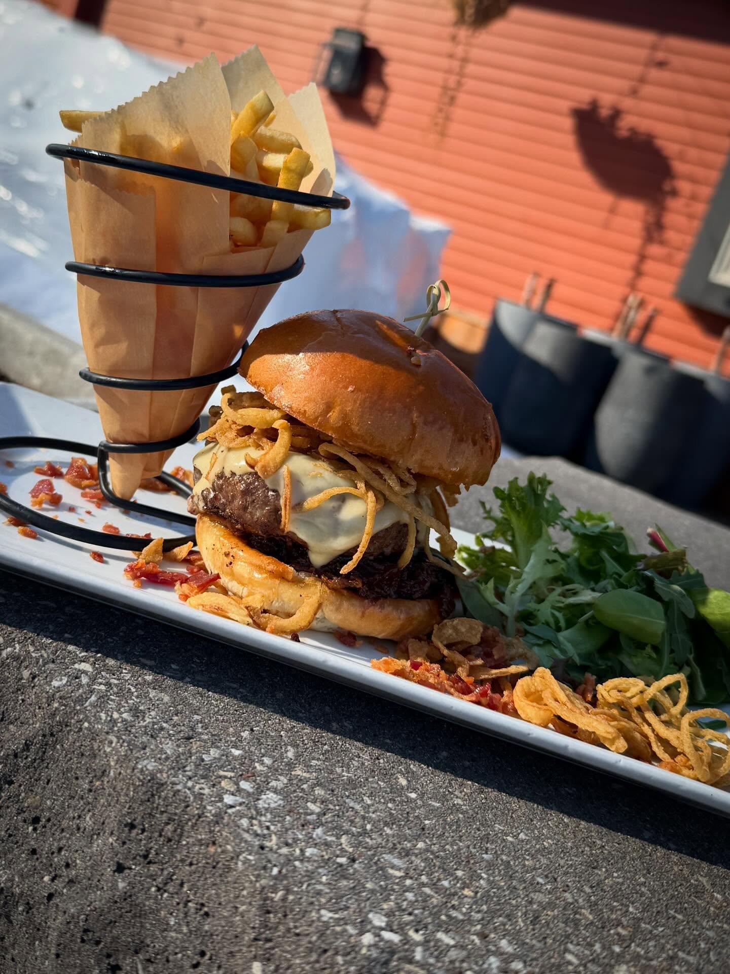 Jet Stream Jam Burger- Half pound hand pressed angus beef on a brioche bun, topped with smoked gruyere cheese, bourbon bacon jam and crispy onion straws. Served with French cut fries