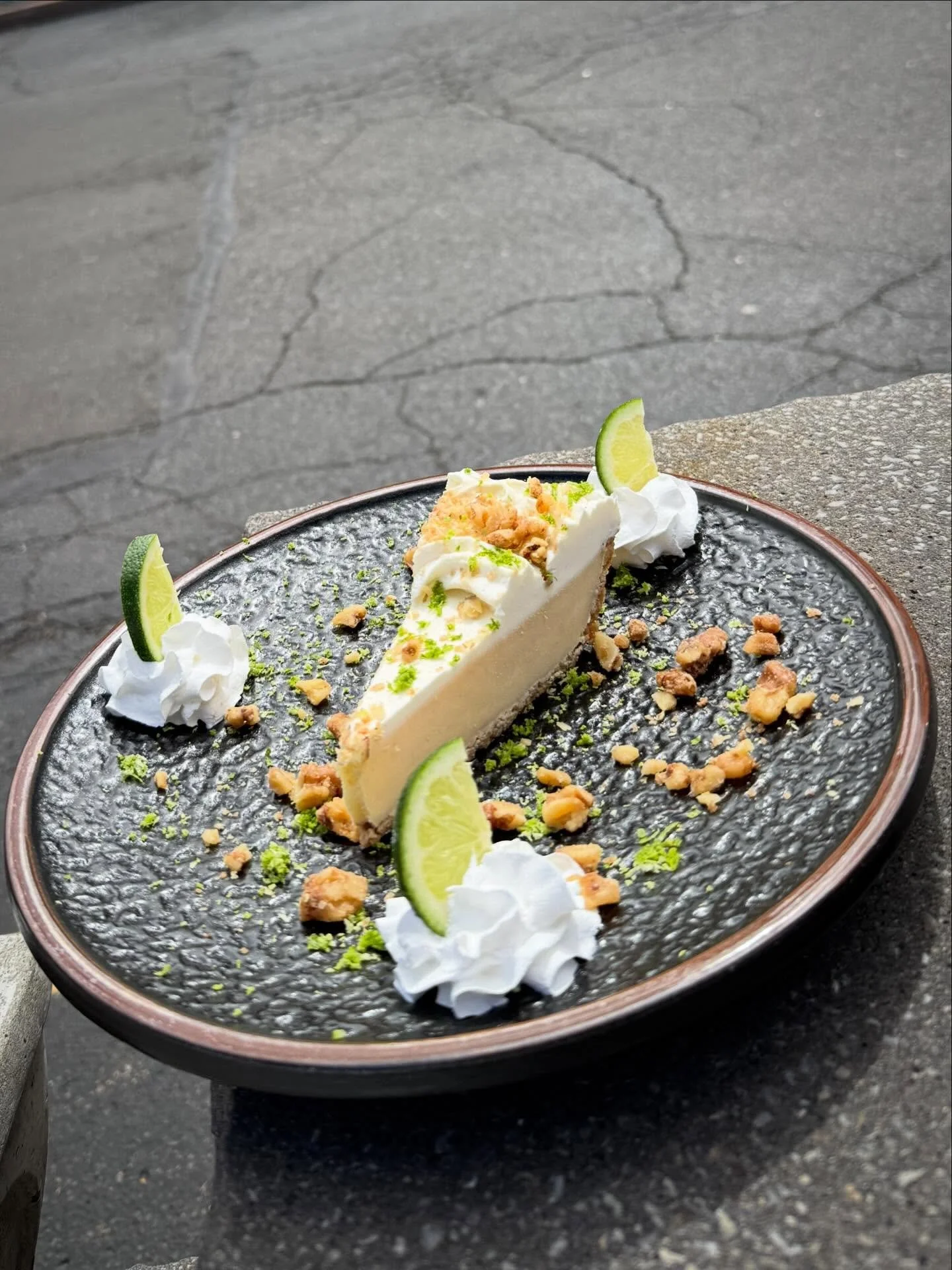 Key Lime Pie- Graham cracker almond pie crust layered with Key lime custard topped with a lightly whipped meringue. Finished with chopped walnuts and fresh lime zest
