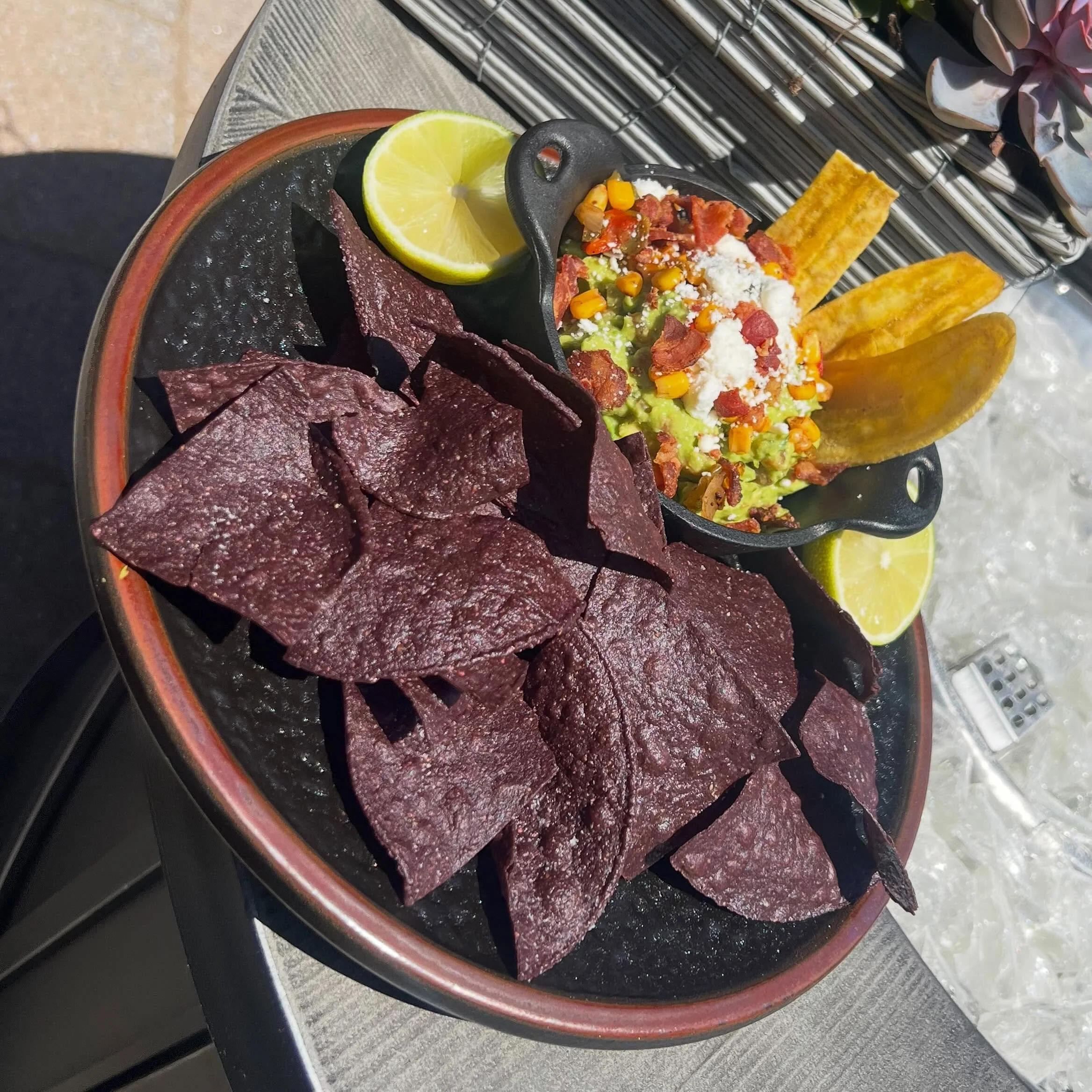 Fire Roasted Guacamole- Ripe avocados smashed with tomatoes, red onion, jalape&ntilde;o, cilantro and fresh lime. Finished with fire roasted corn, smokey bacon and cotija cheese. Served with house made agave chips.