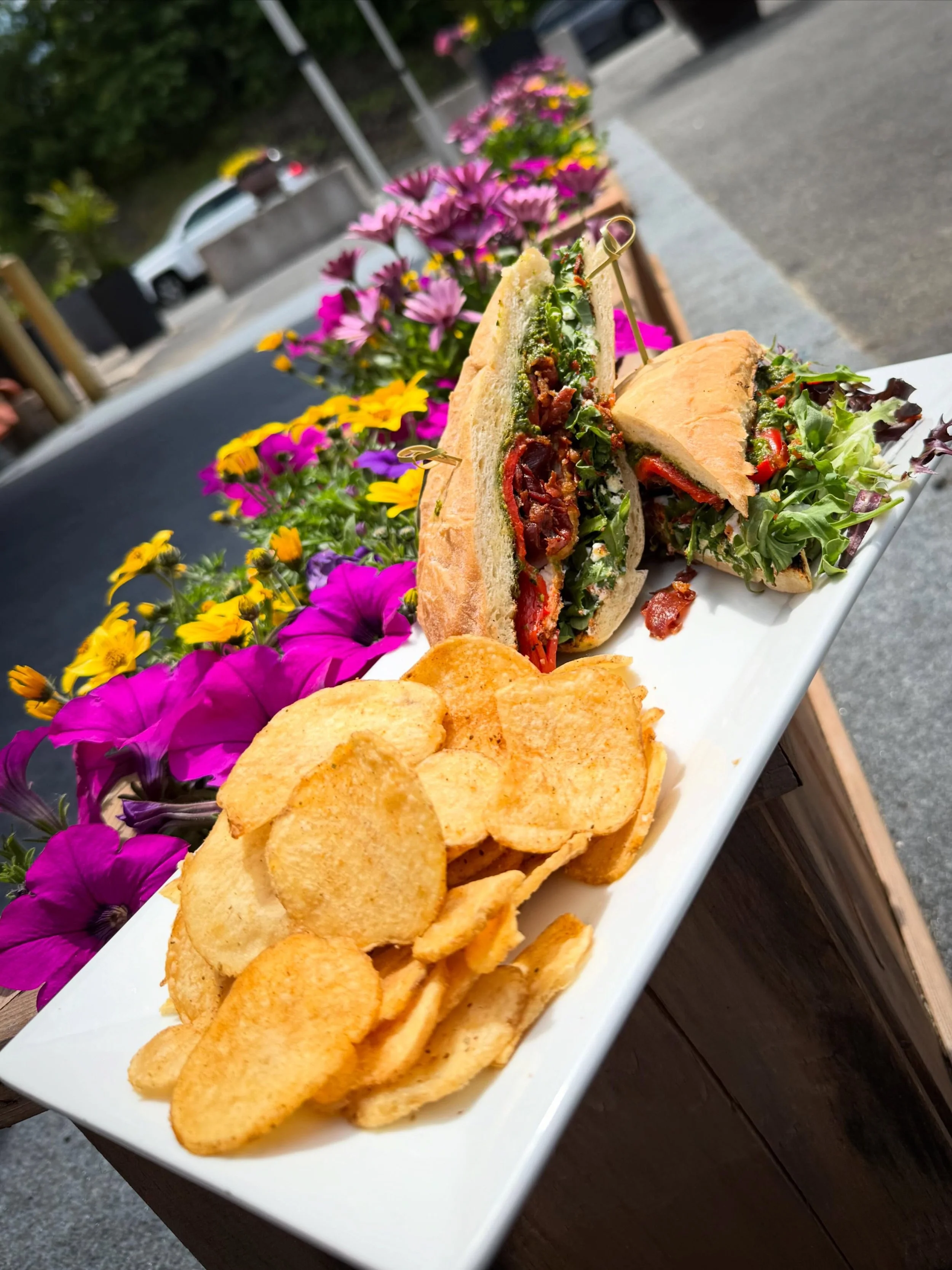 The Monkey Business- Crispy panko fried chicken stacked with whipped ricotta, pistachio pesto, crispy prosciutto, roasted red peppers and baby arugula on grilled ciabatta bread. Finished with house-made potato chips