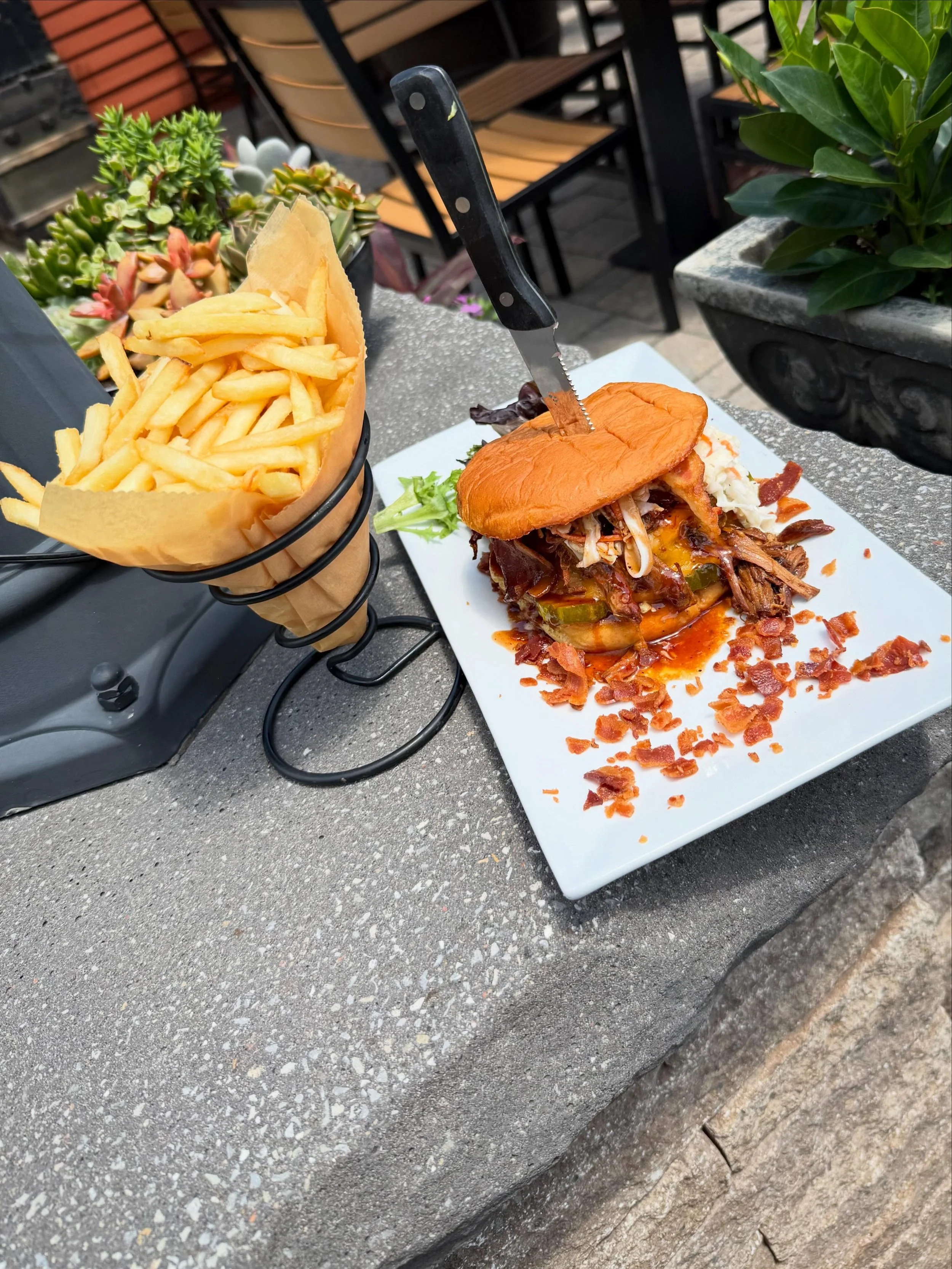 Barnstormer Burger - A half-pound Angus burger loaded with melted cheddar, pulled pork, pickles, double smoked bacon, and crunchy coleslaw. Finished with BBQ sauce and served on a toasted potato bun with French cut fries