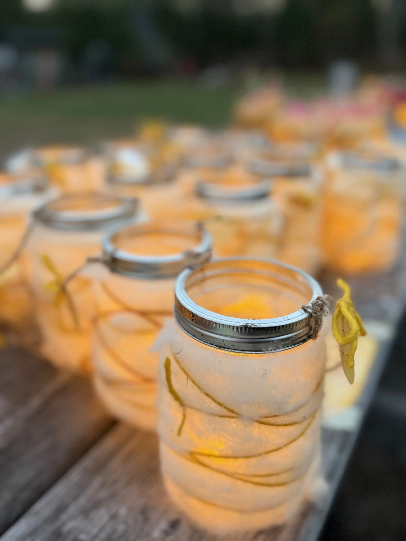 Close-up of small candles with metal holders, lit and placed in a row, with a blurred background.