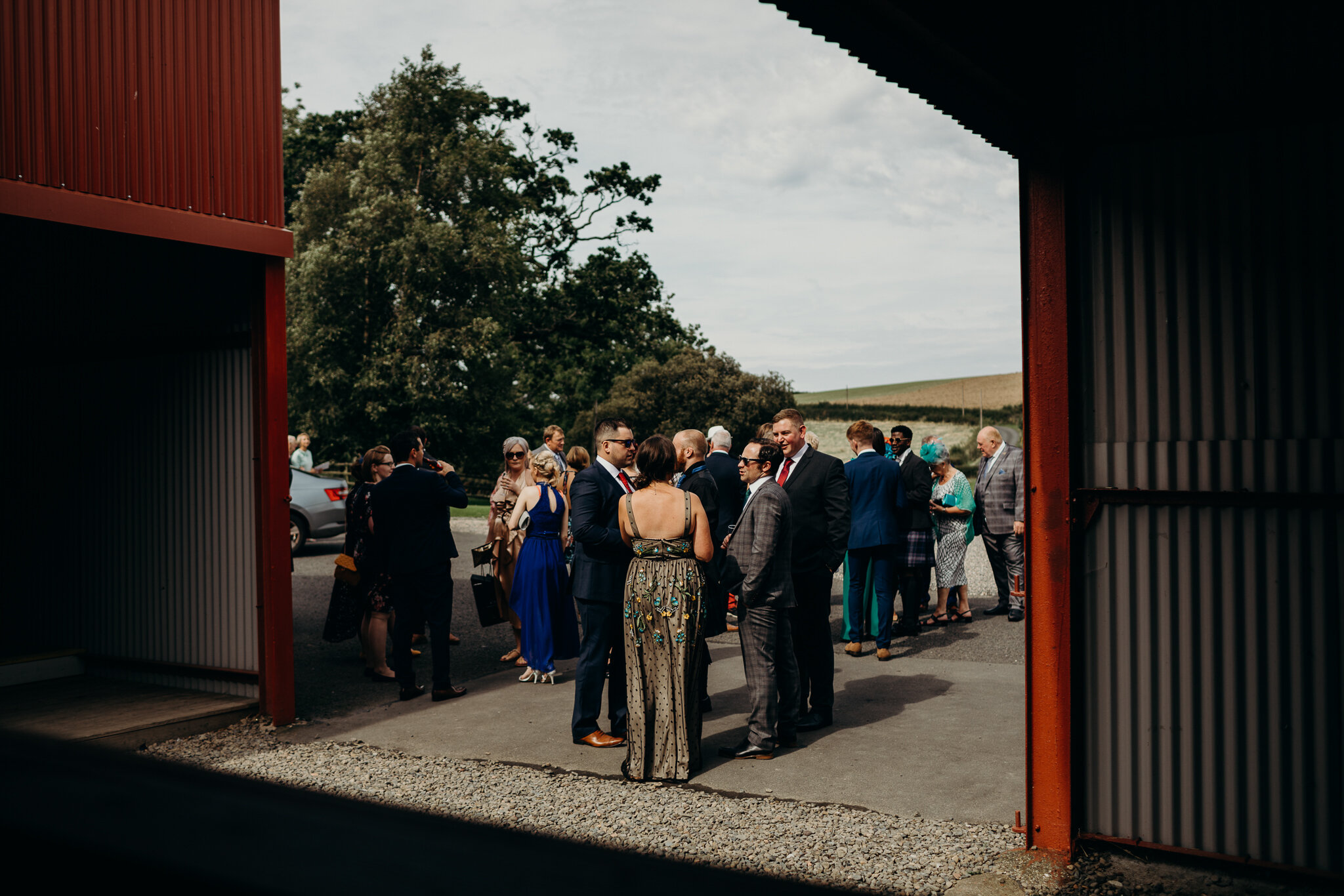 guests gathering in sunlight outdoors at dalduff farm barn for humanist wedding photographed by wedding photographer ayrshire scotland