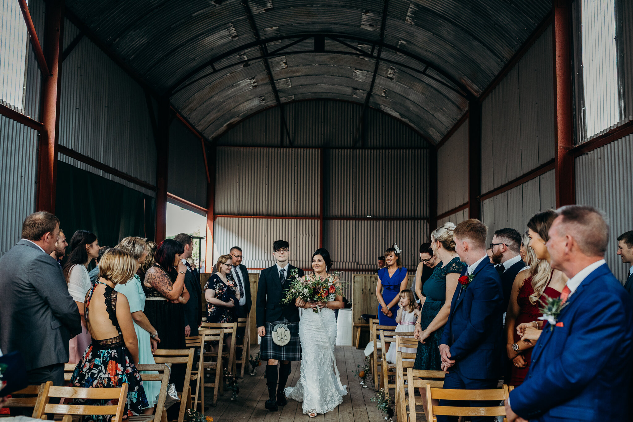 bride walking down the aisle during ceremony outdoors in barn at dalduff farm photographed by wedding photographer ayrshire scotland