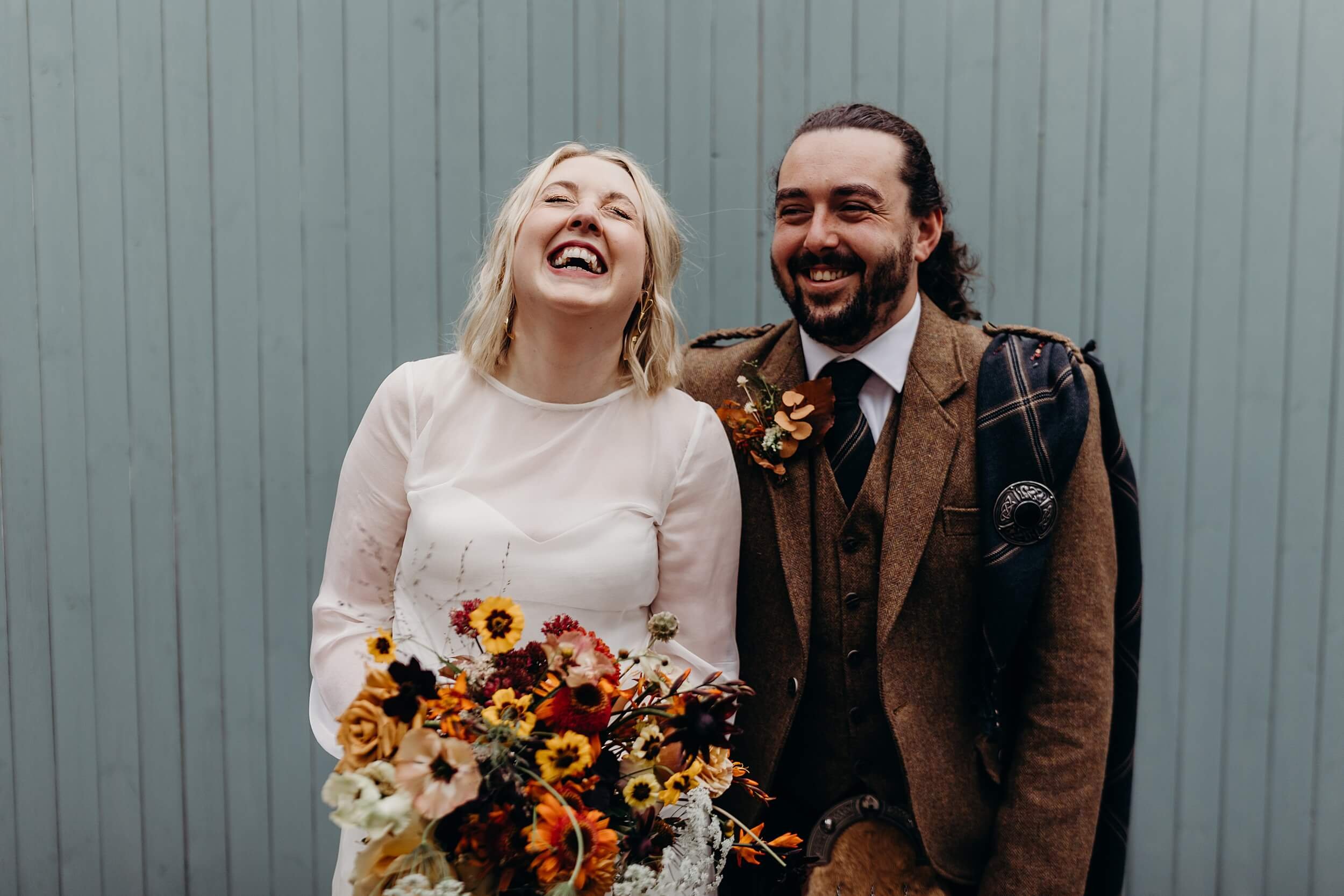 bride and groom laugh on their wedding day in front of colourful background natural wedding photography glasgow scotland