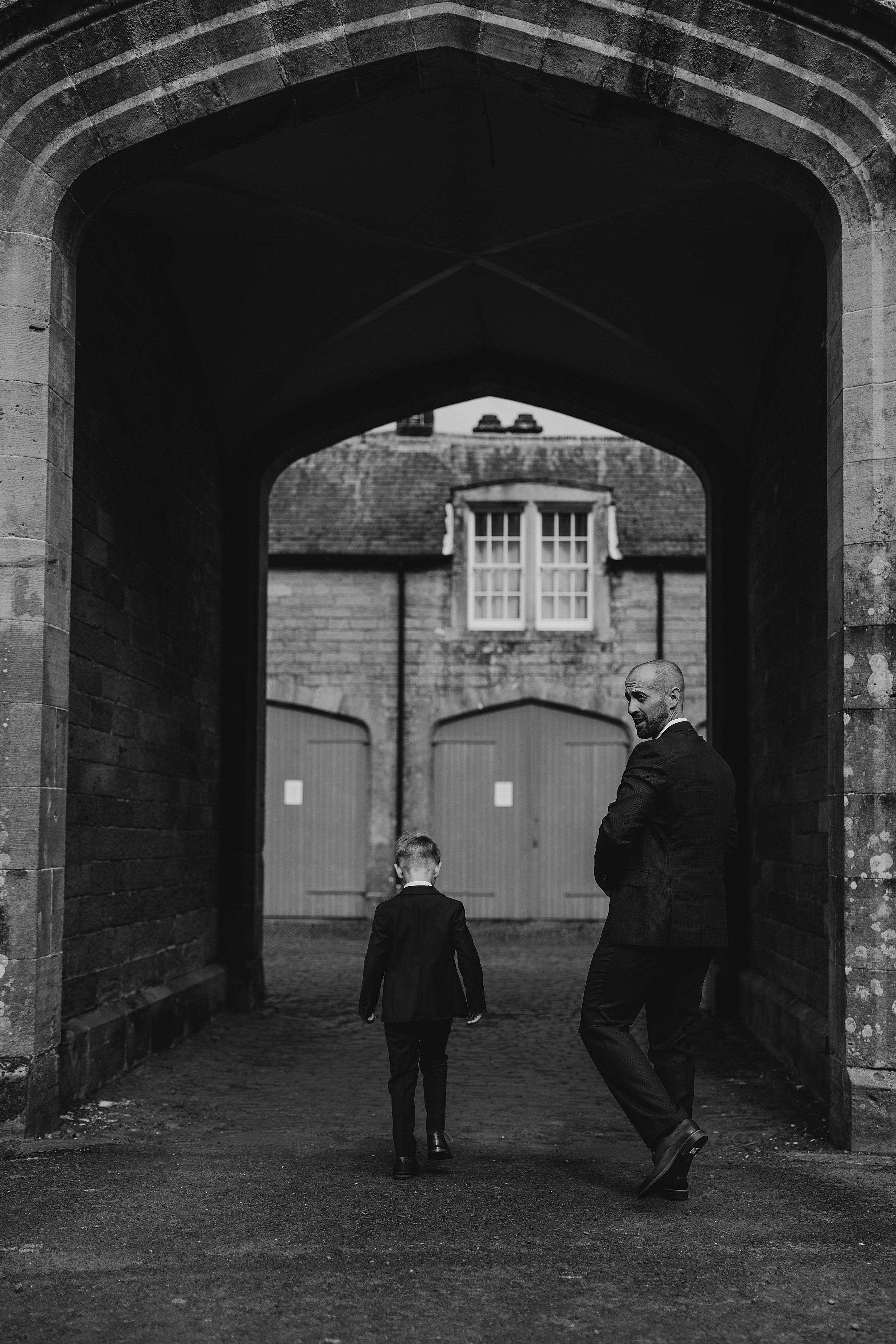 dalfduff wedding photos showing groom and son walking through stone archway on the way to wedding ceremony at dalduff barn