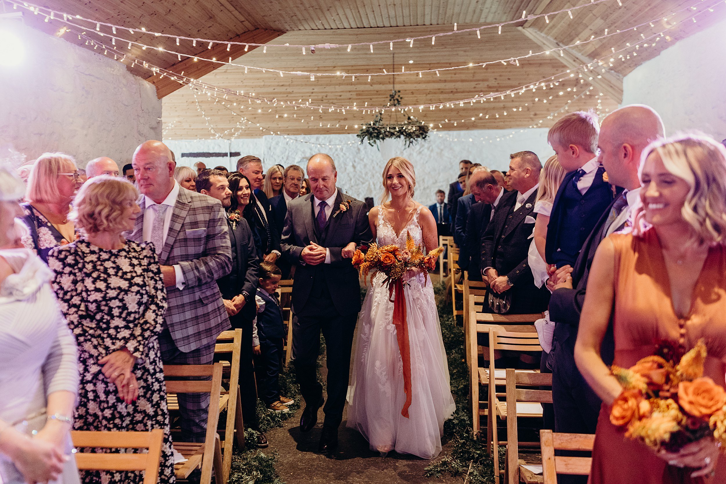 bride walking down the aisle with her father inside dalduff barn shown in dalduff farm wedding photos