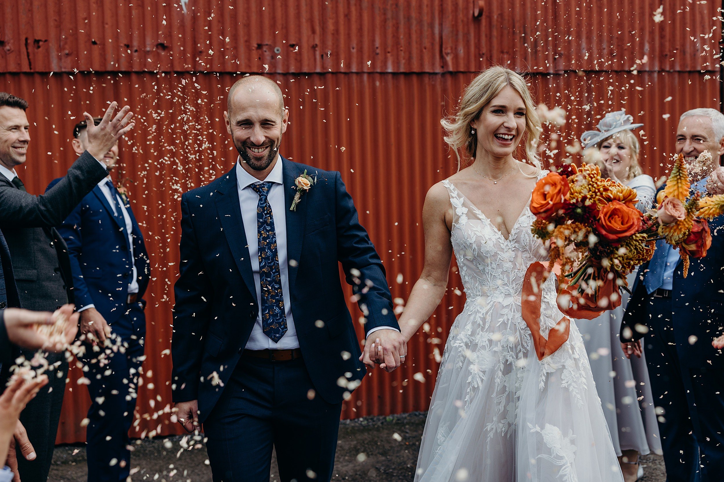 dalduff farm wedding photos showing bride and groom smiling and walking under confetti throw outside dalduff barn