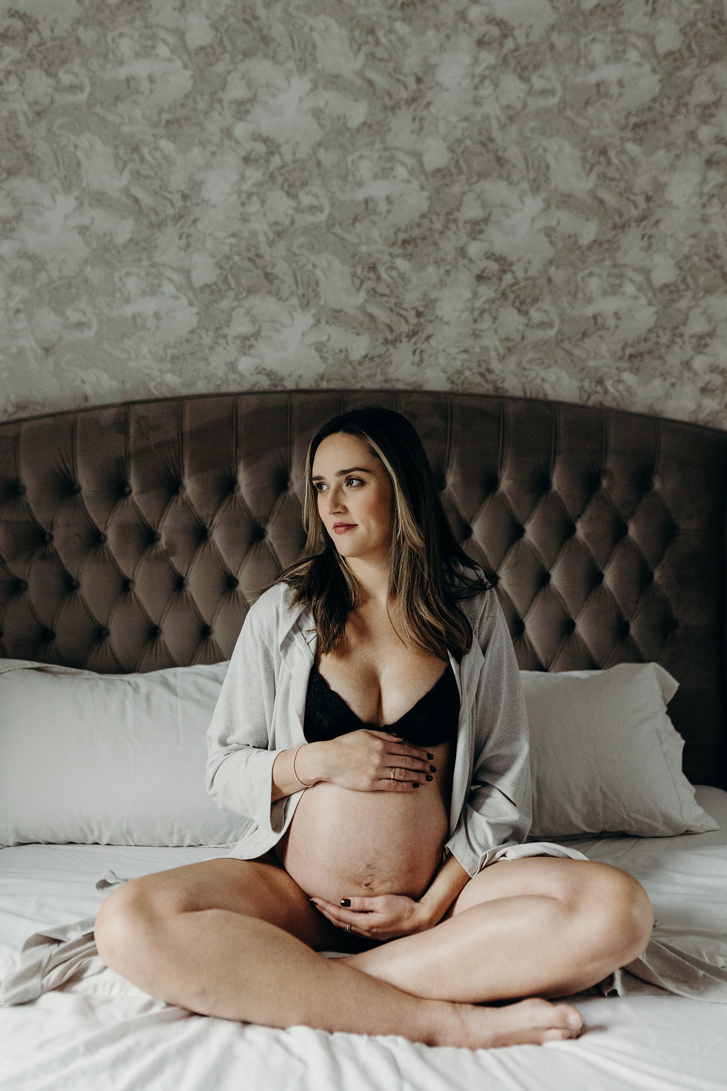 mum to be sitting with her legs crossed on bed during maternity photo session by maternity photographer glasgow