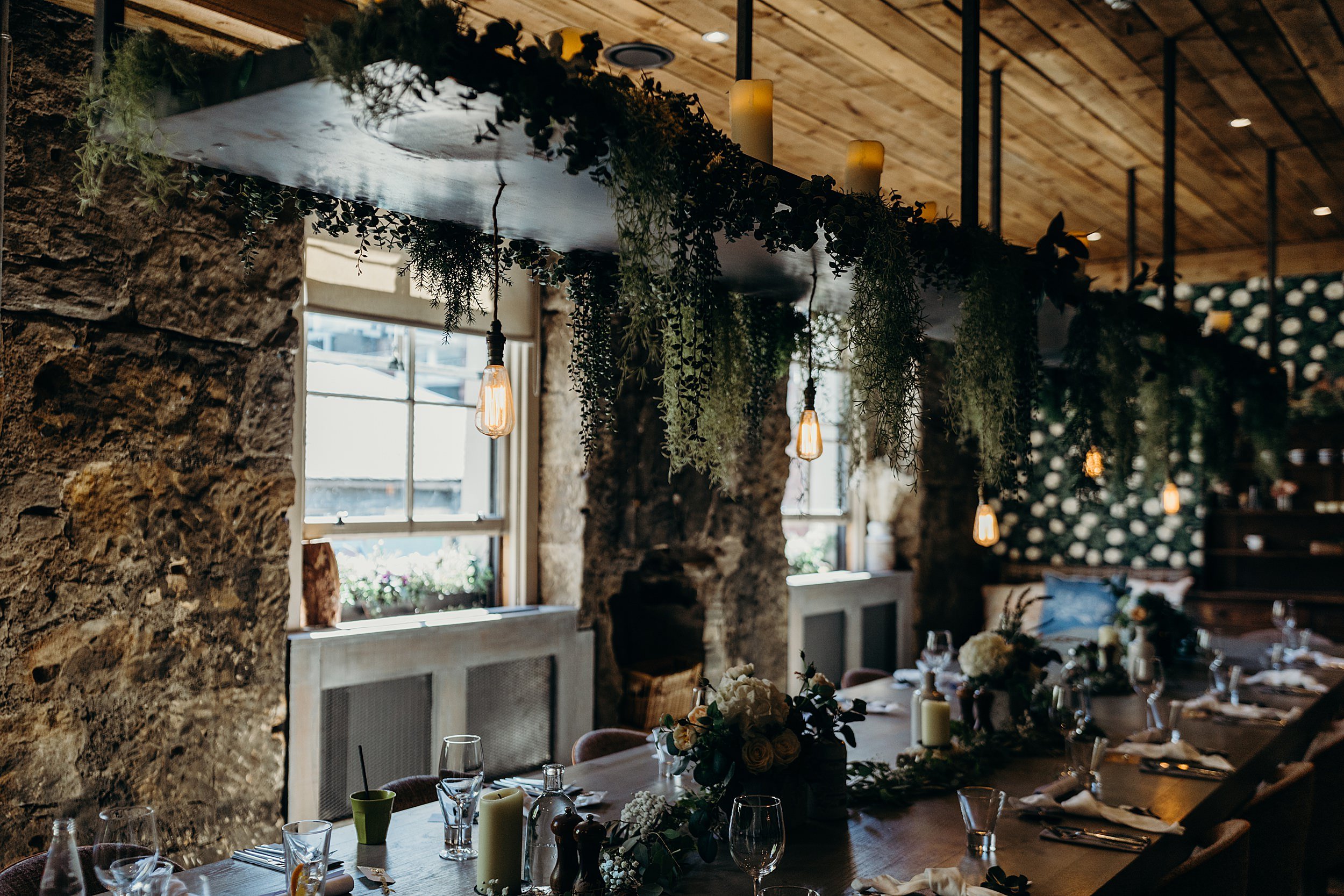 dining table in the scullery at the bothy glasgow wedding decorated with green foliage and pendant lights for a micro wedding in the west end glasgow