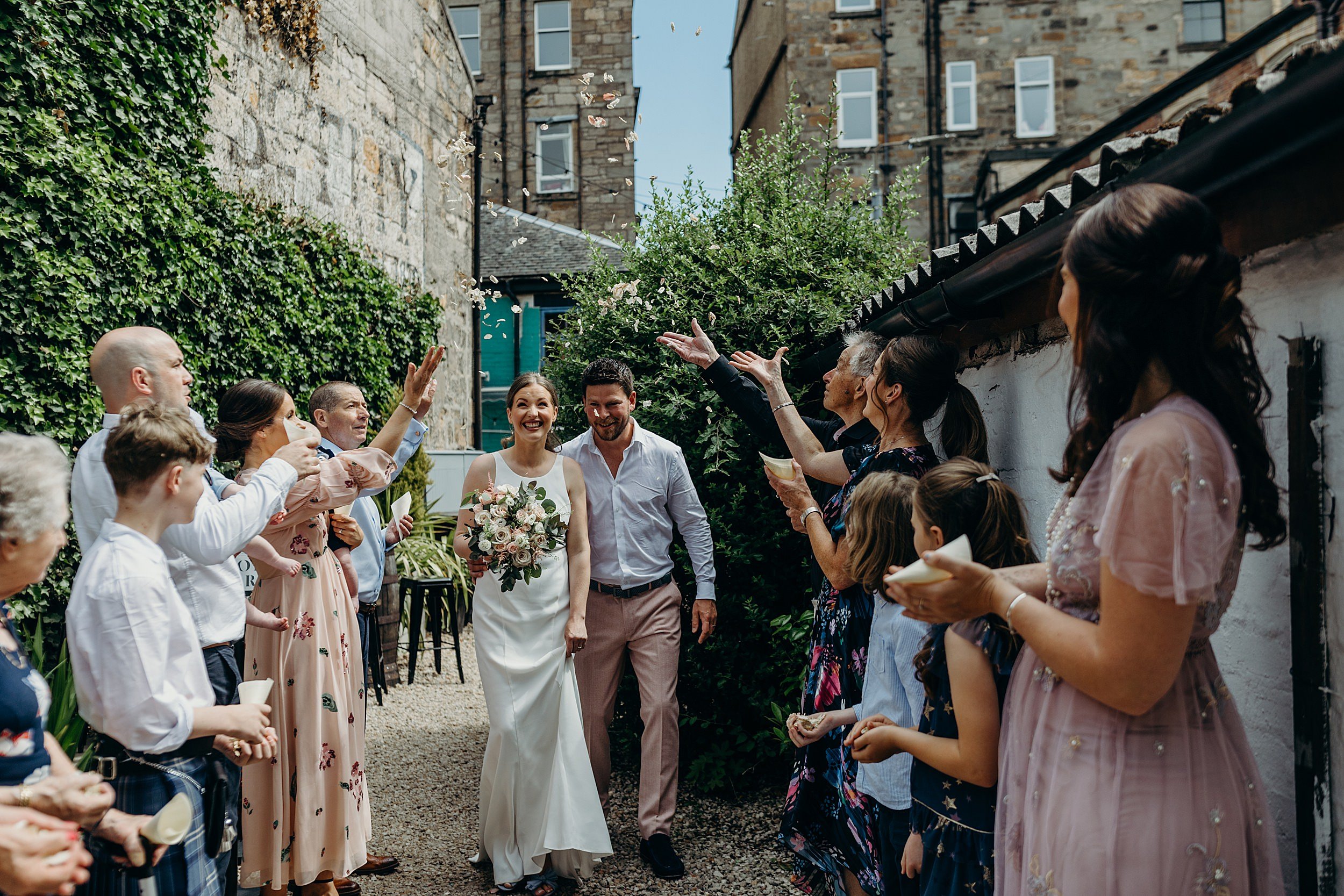 bride and groom walking through colourful confetti throw at the bothy glasgow wedding outside during their micro wedding