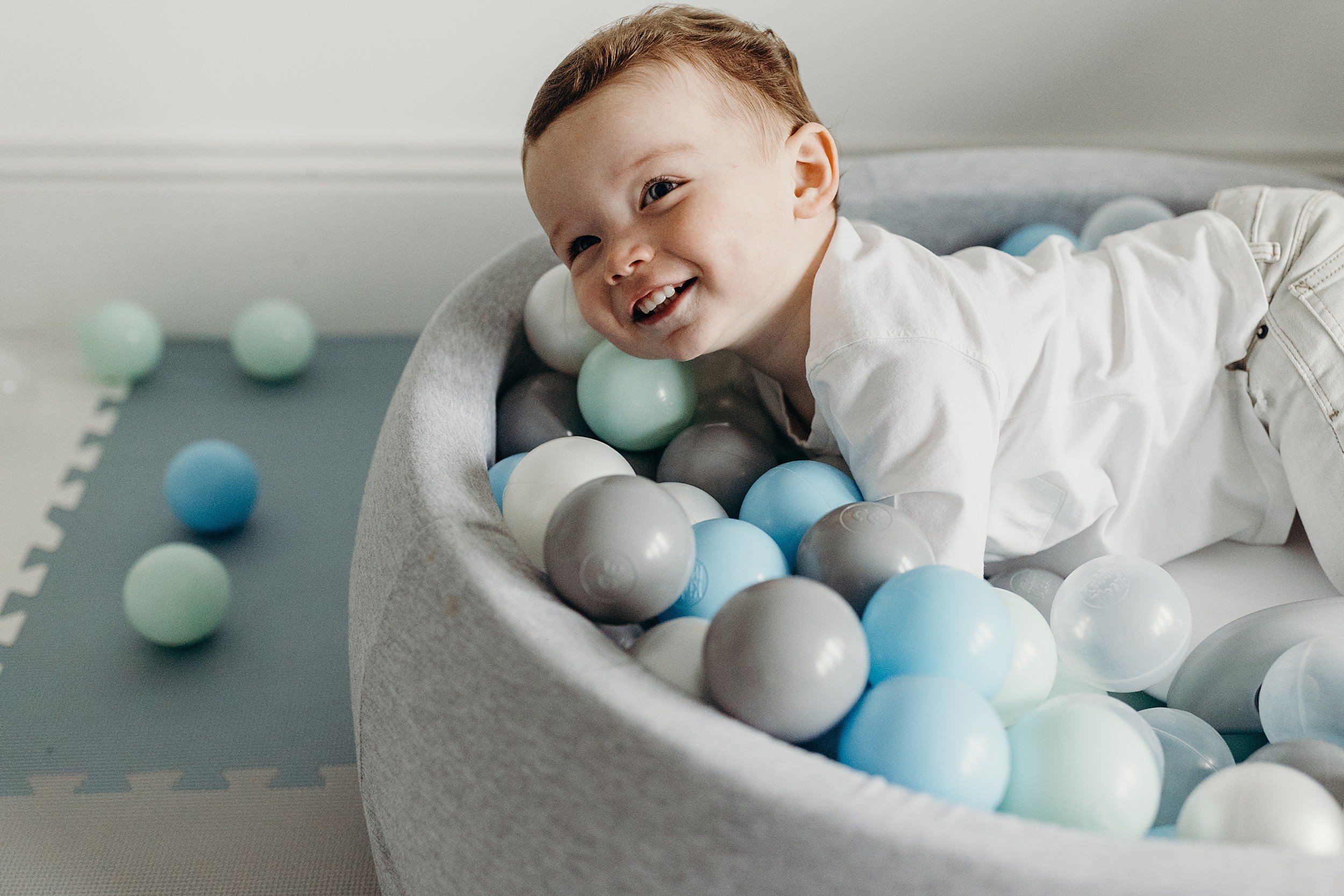 family photographer glasgow captures toddler boy with red hair playing in a ball pool 