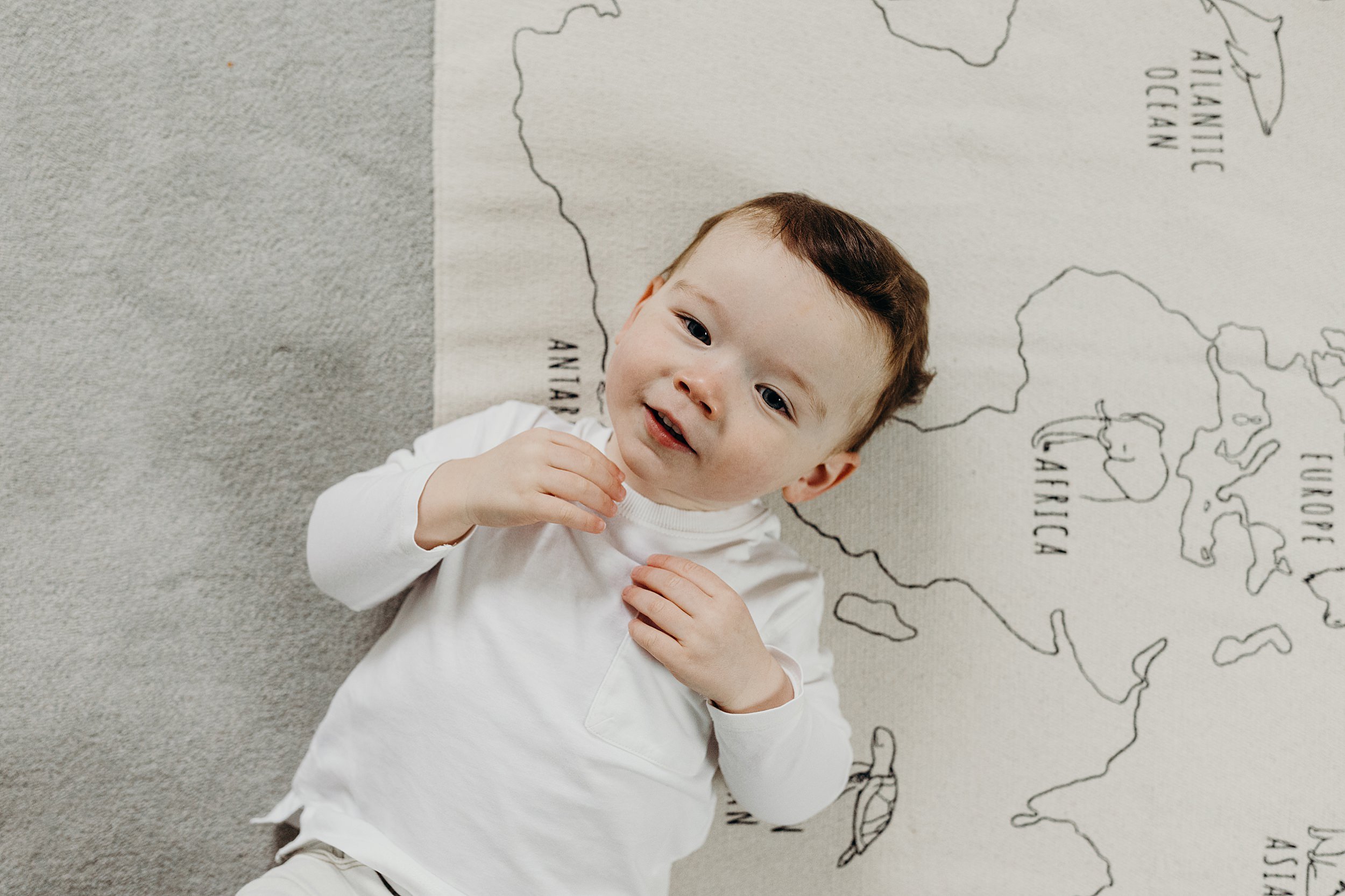 family photographer glasgow captures toddler boy with red hair lying on a map of the world mat
