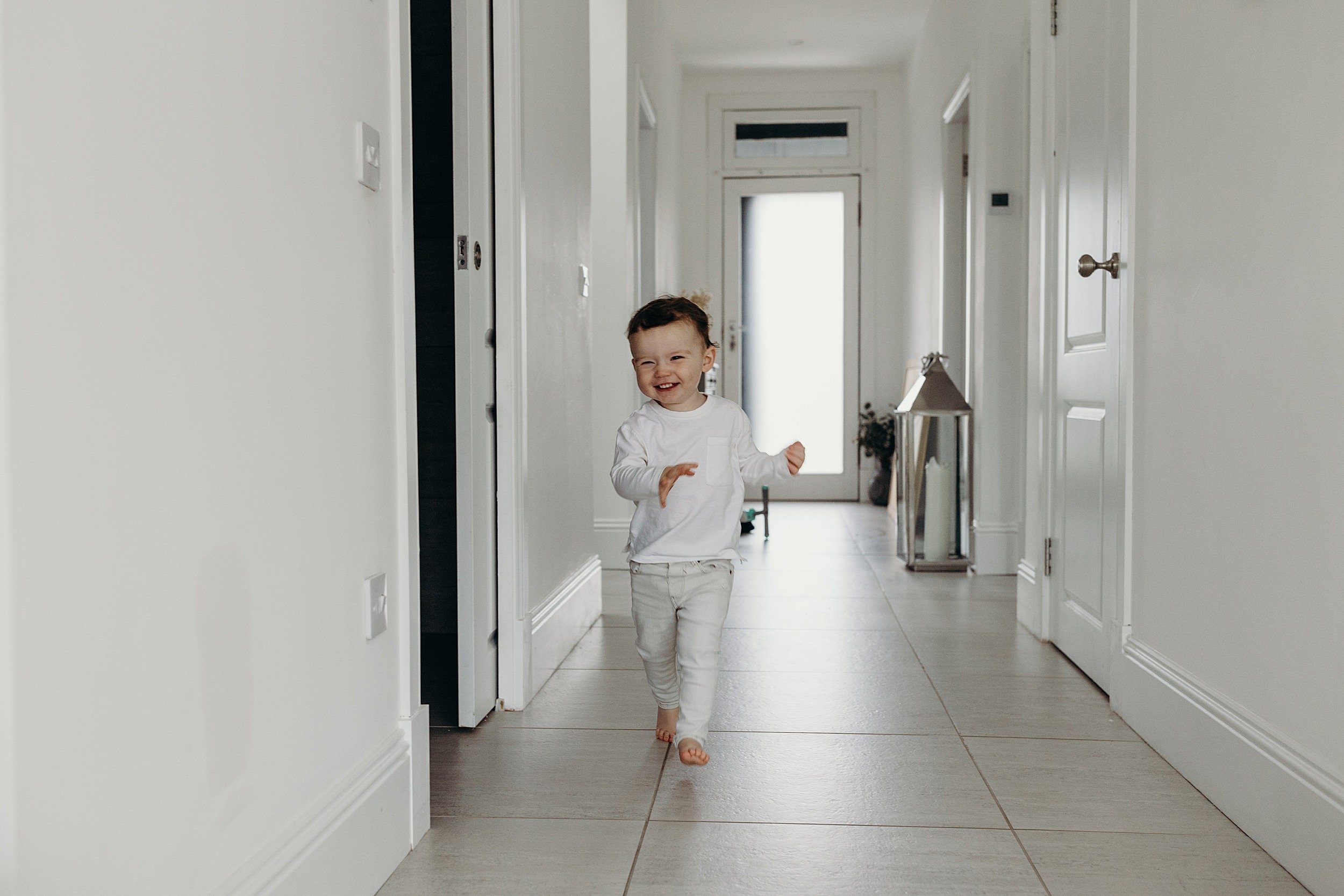 family photographer glasgow scotland captures toddler boy with red hair running in hallway laughing