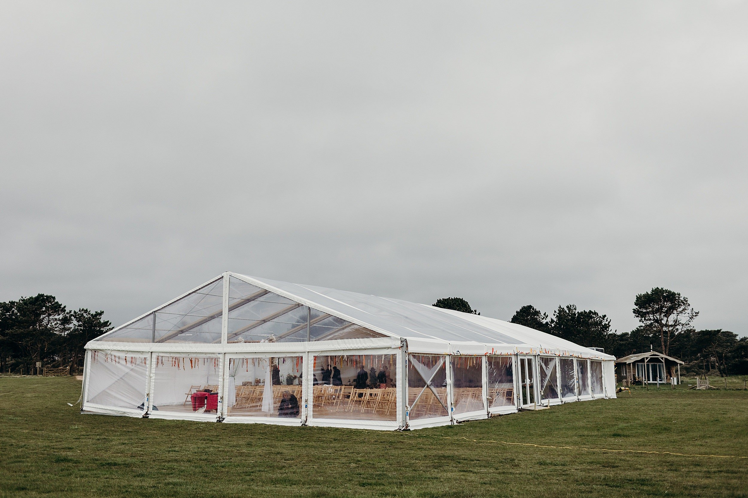 exterior outside view of a white marquee with transparent sides in a green field at harvest moon wedding venue in dunbar scotland