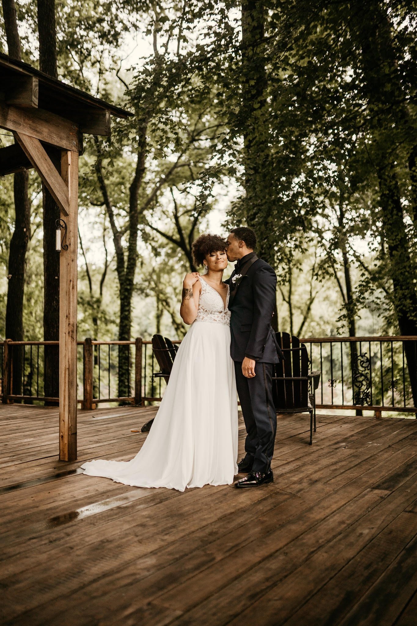 Groom-Cheek-Kisses-Bride-On-Wood-Deck.jpg