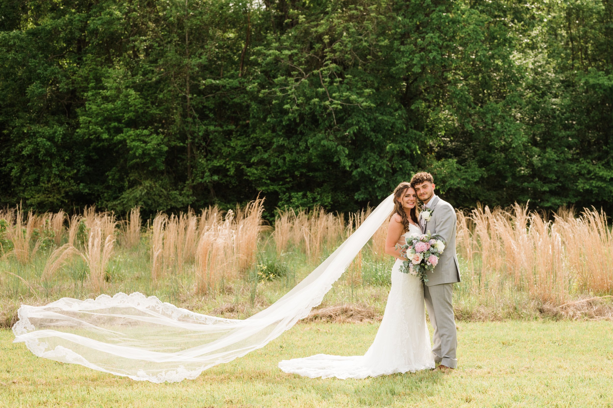 Bridal-Couple-Flowing-Veil-In-Field-.jpg