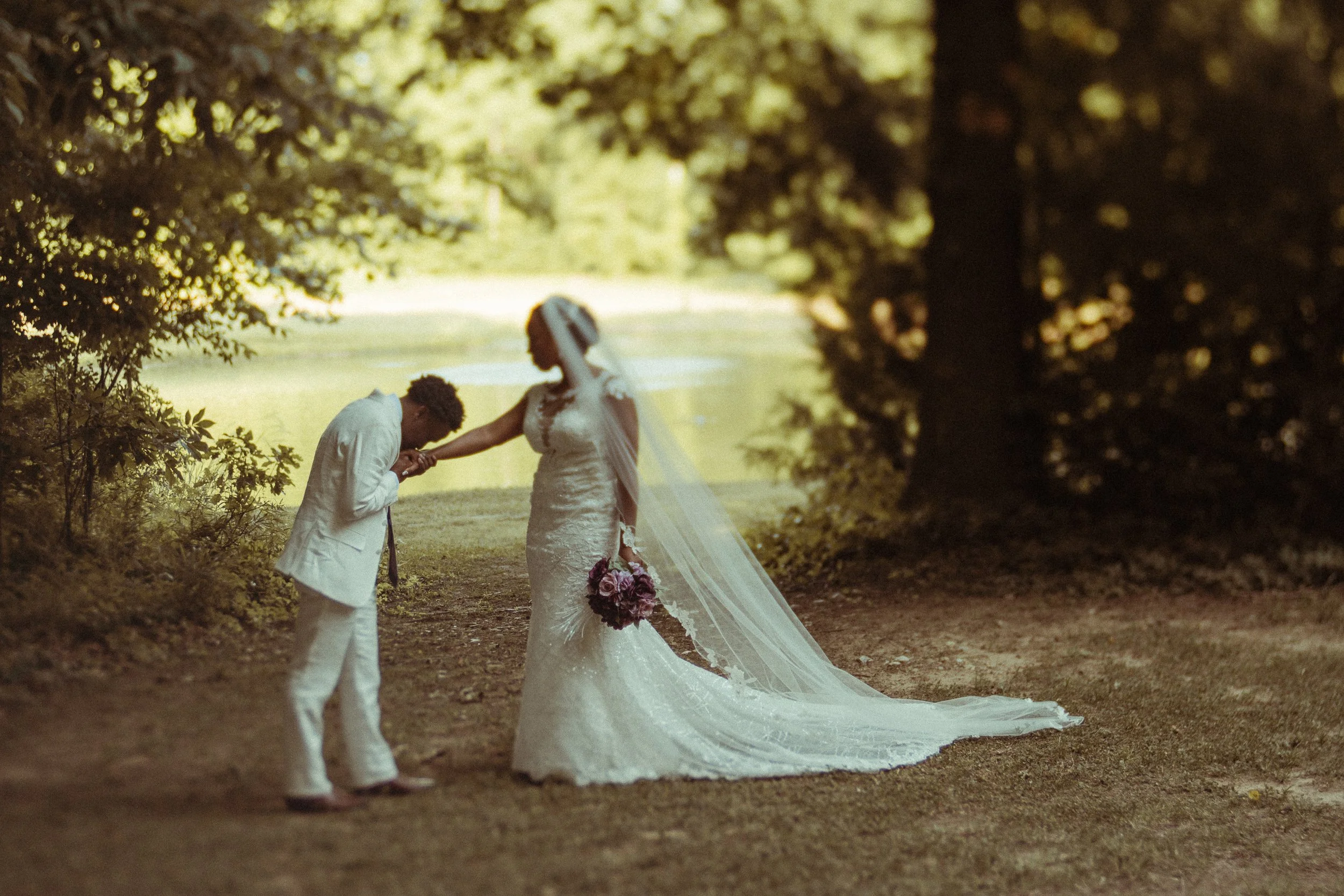 Groom kisses brides hand in front of pond with water-fountain