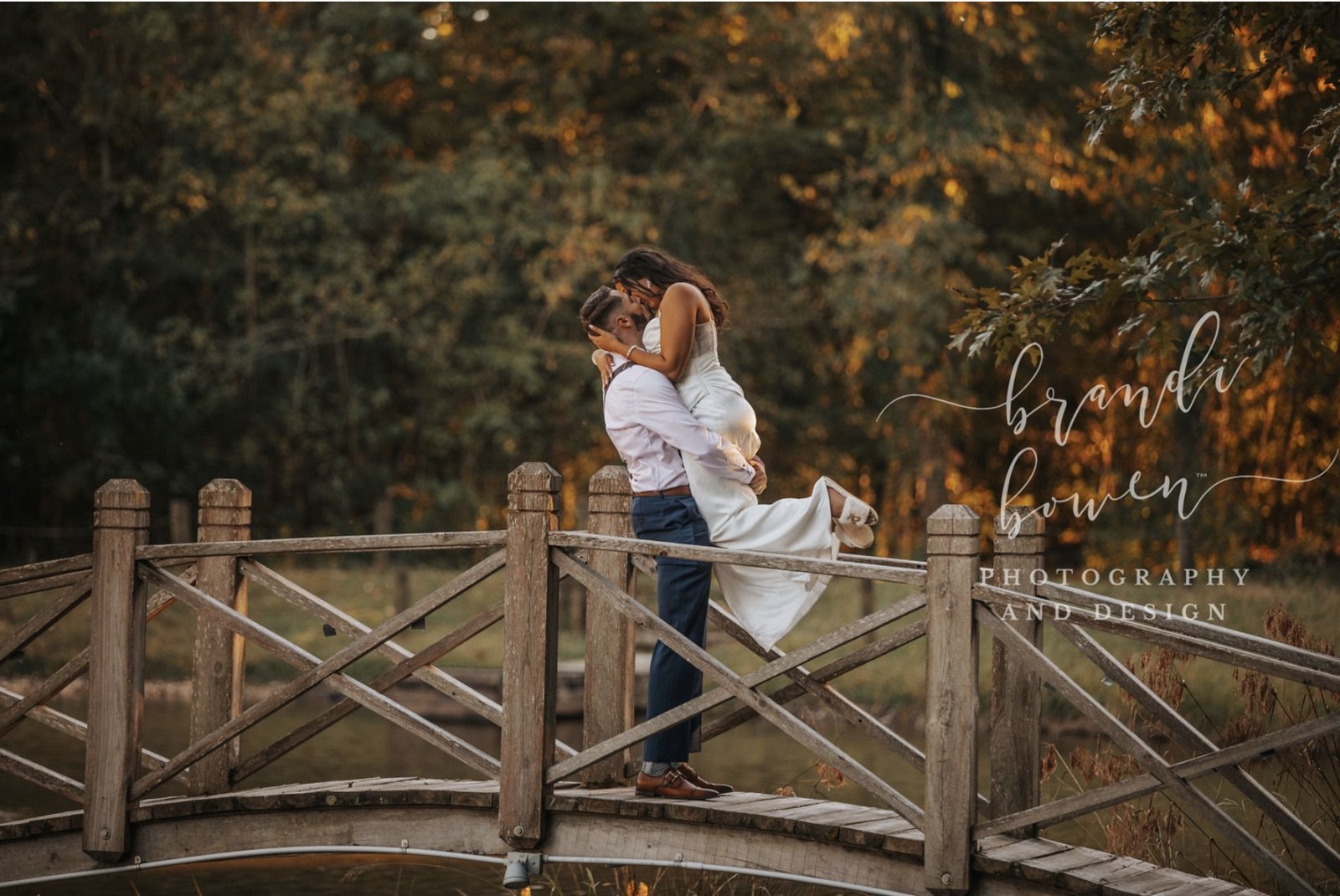 Groom lifts bride on wood footbridge at The Catlett Farm