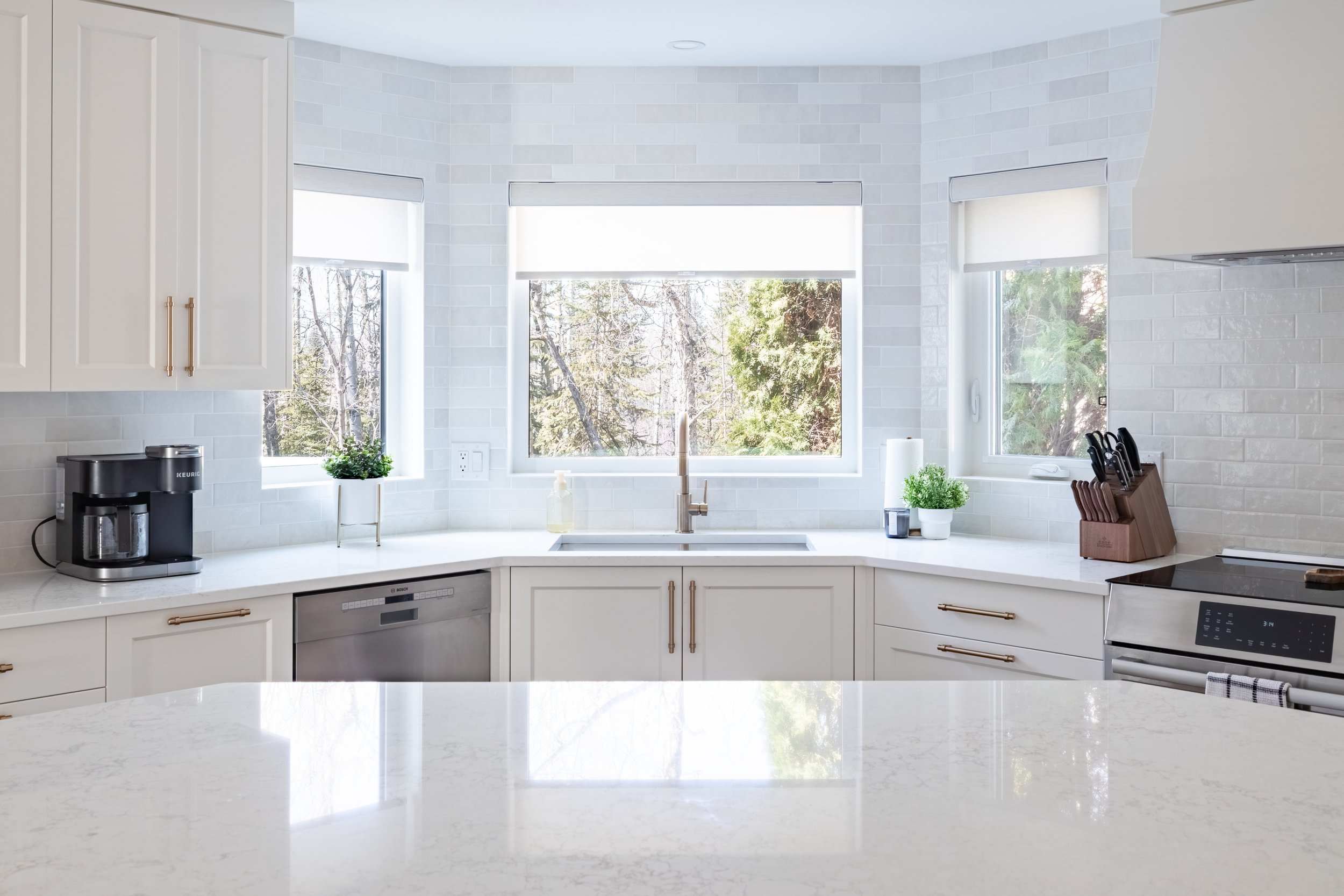 A view of the kitchen Sink included subway backsplash, MDF painted cabinets and quartz countertops.