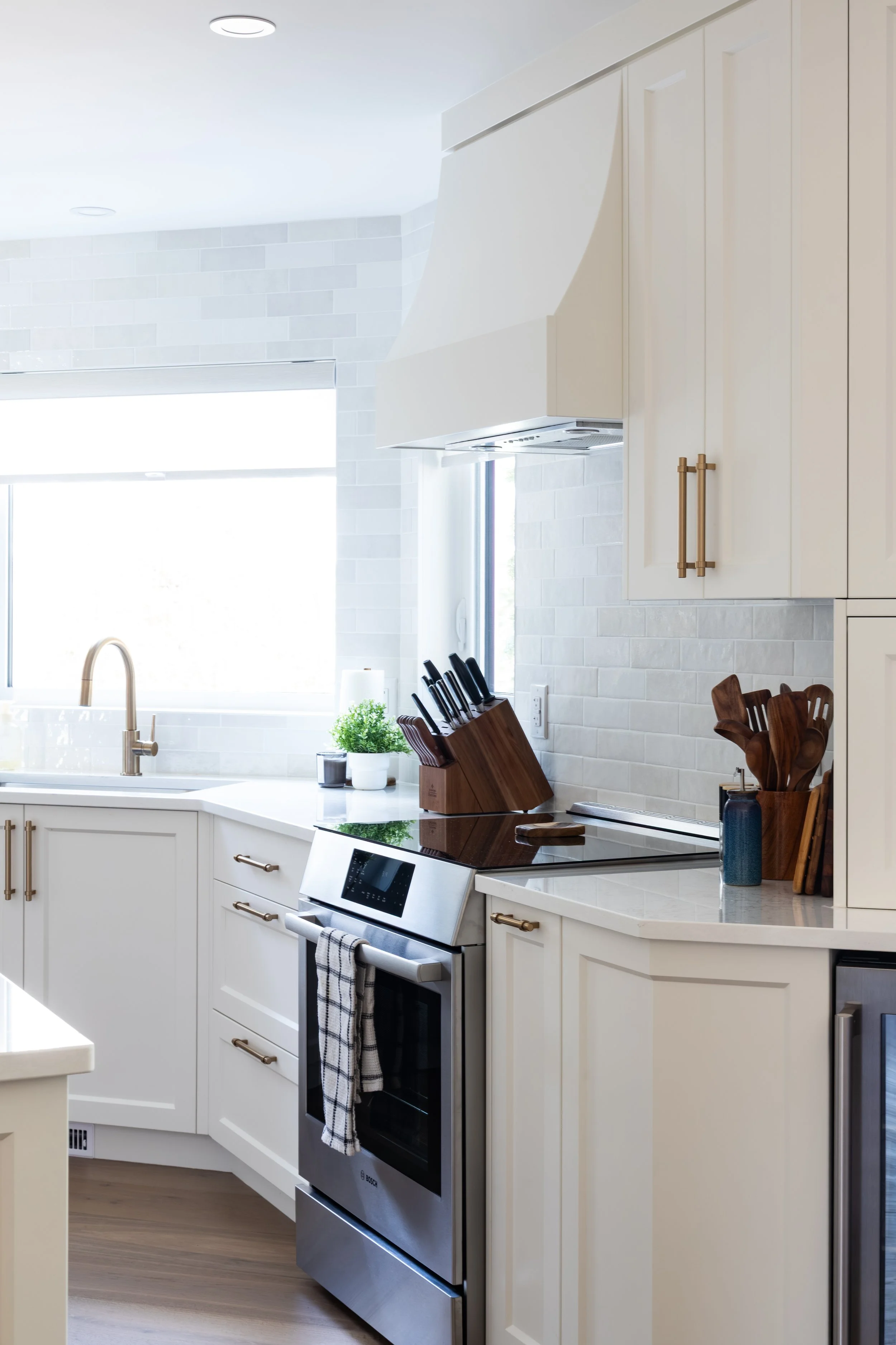 MDF Painted Cabinets in White Dove with custom designed Range Hood and brass hardware.