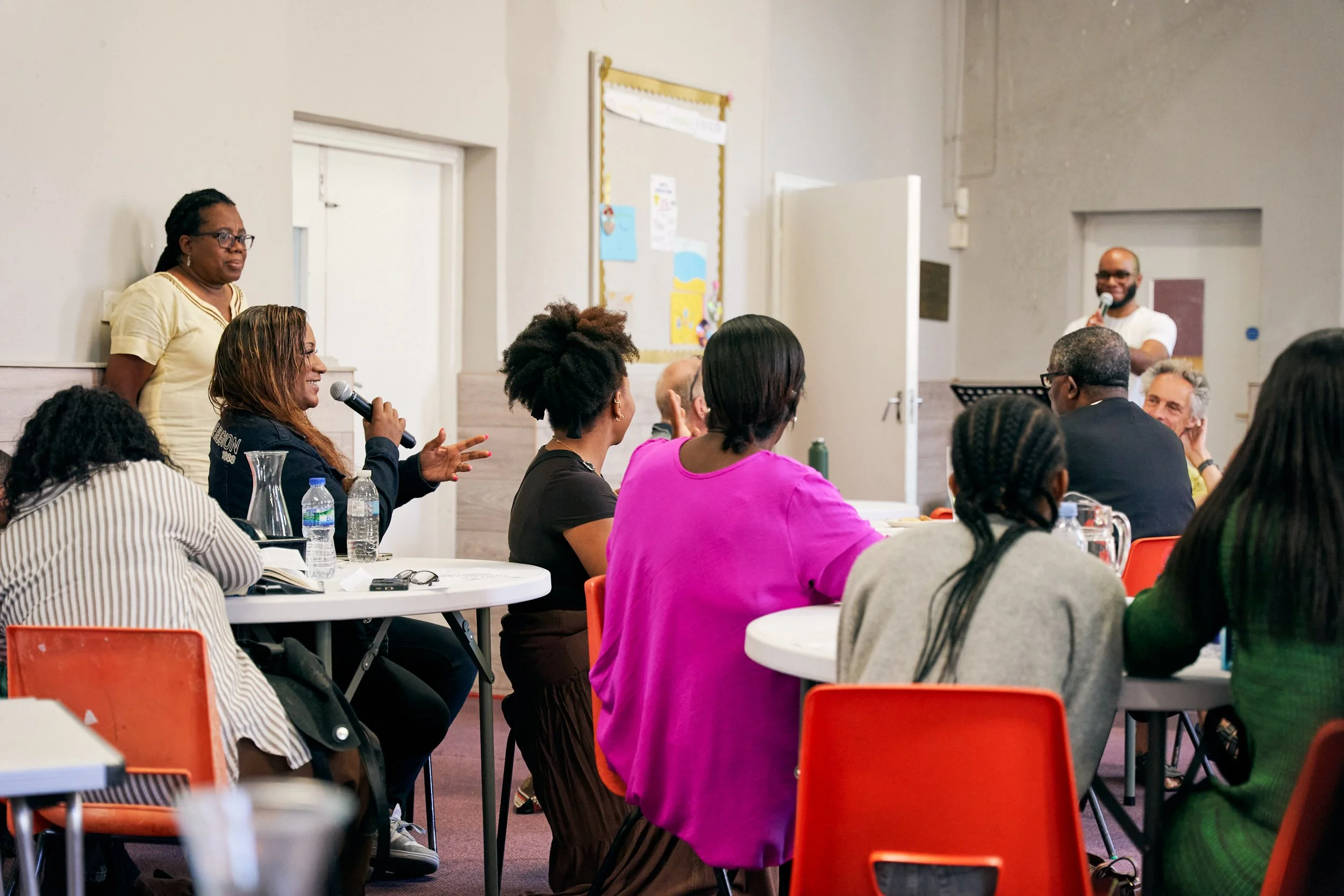 People attending a meeting or workshop in a conference room with a speaker addressing the audience.