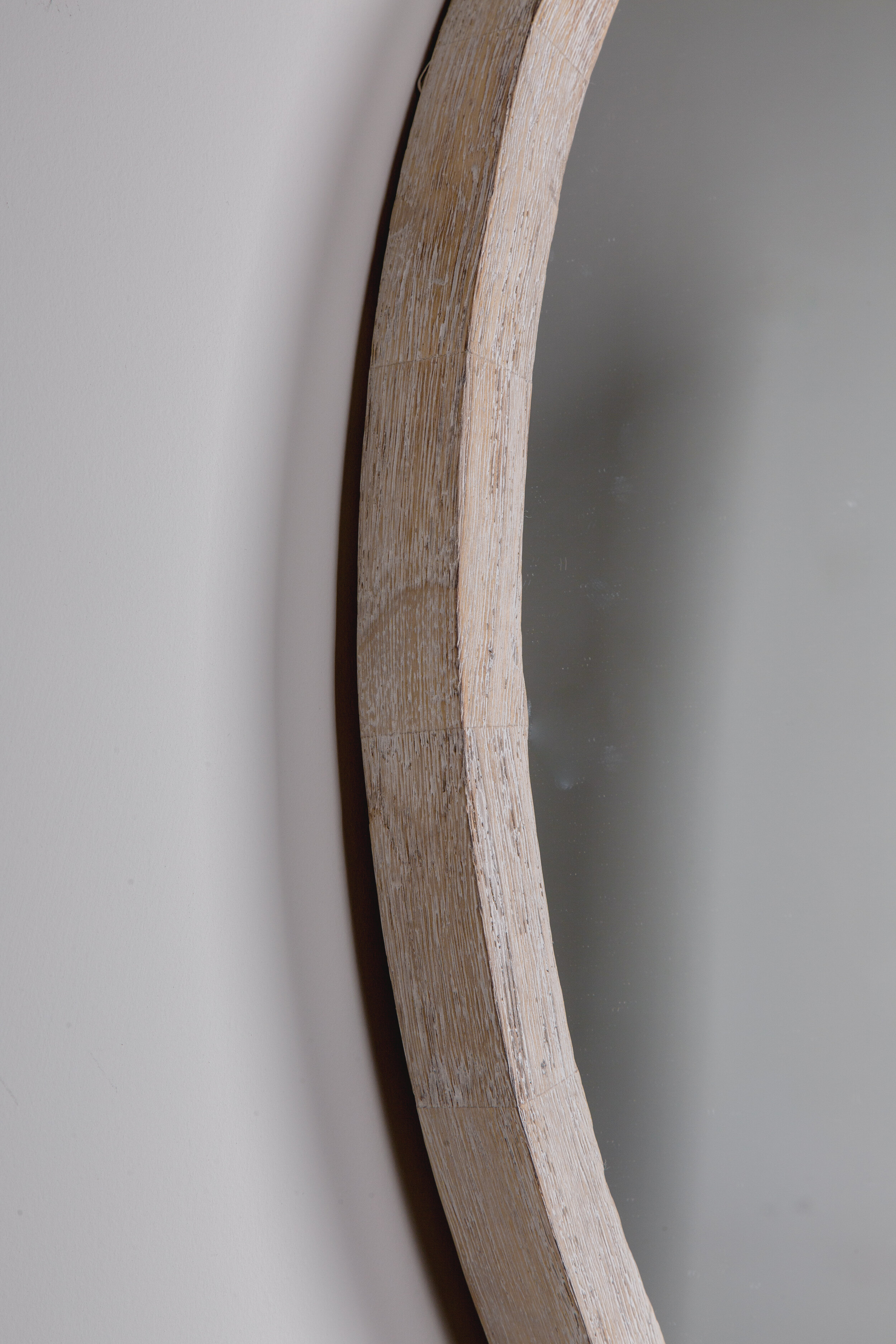 unfinished wooden frame of circular mirror against white wall