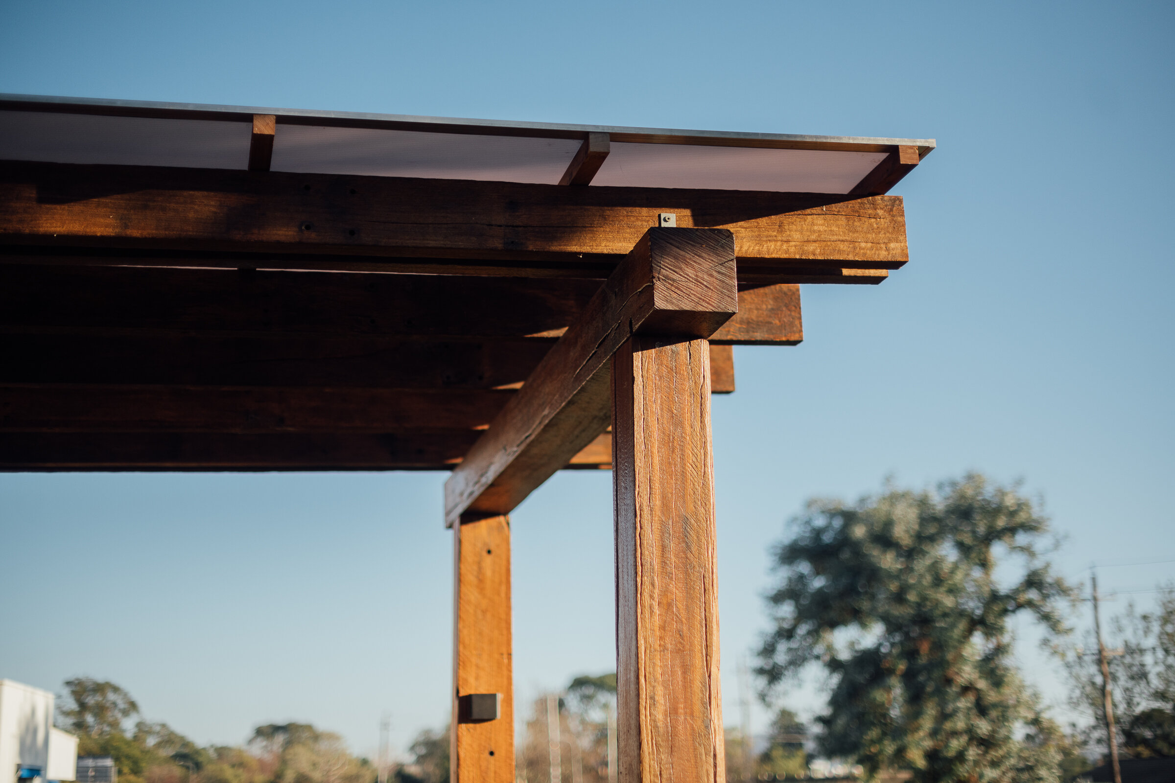 Pergola built with recycled timber posts and beams in focus against the blue sky