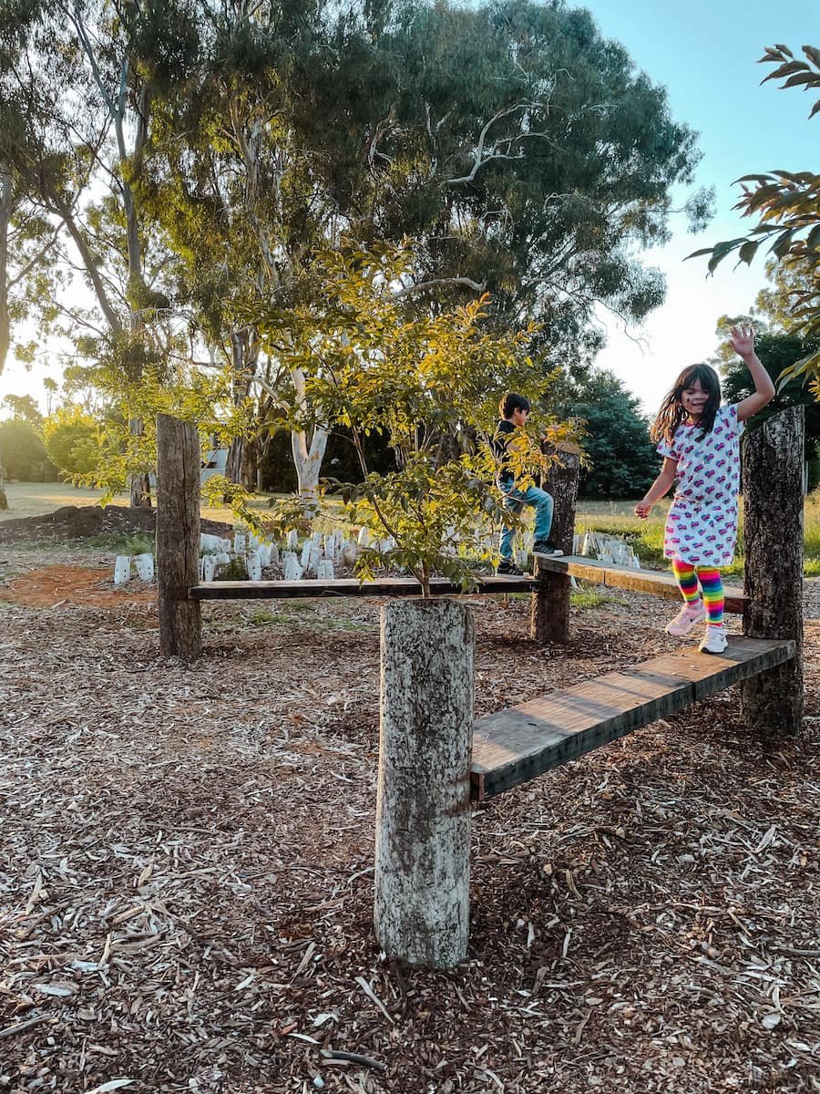 Kids balancing on a recycled timber bench in a park 