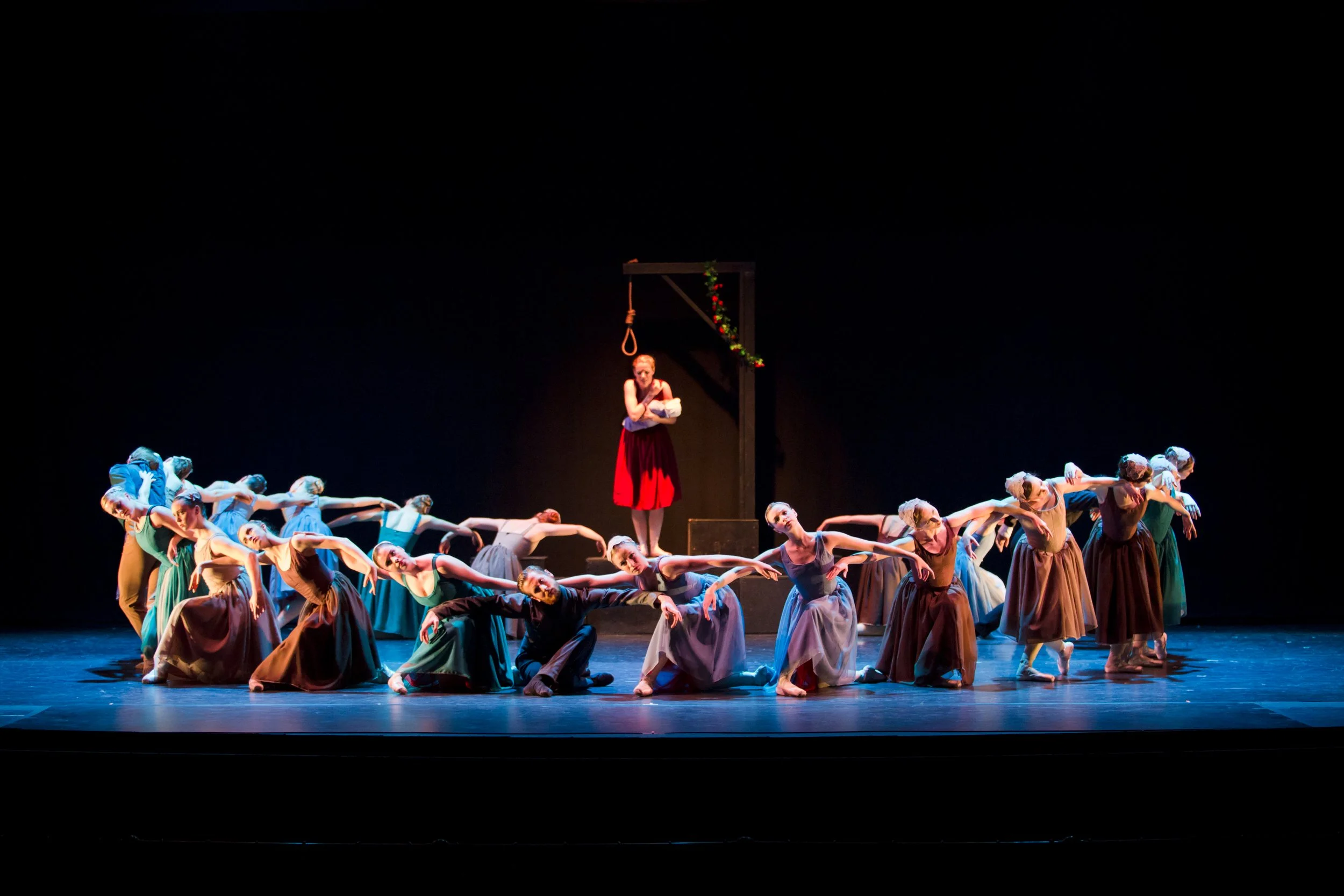 Scarlet: dancers form a ring around a woman