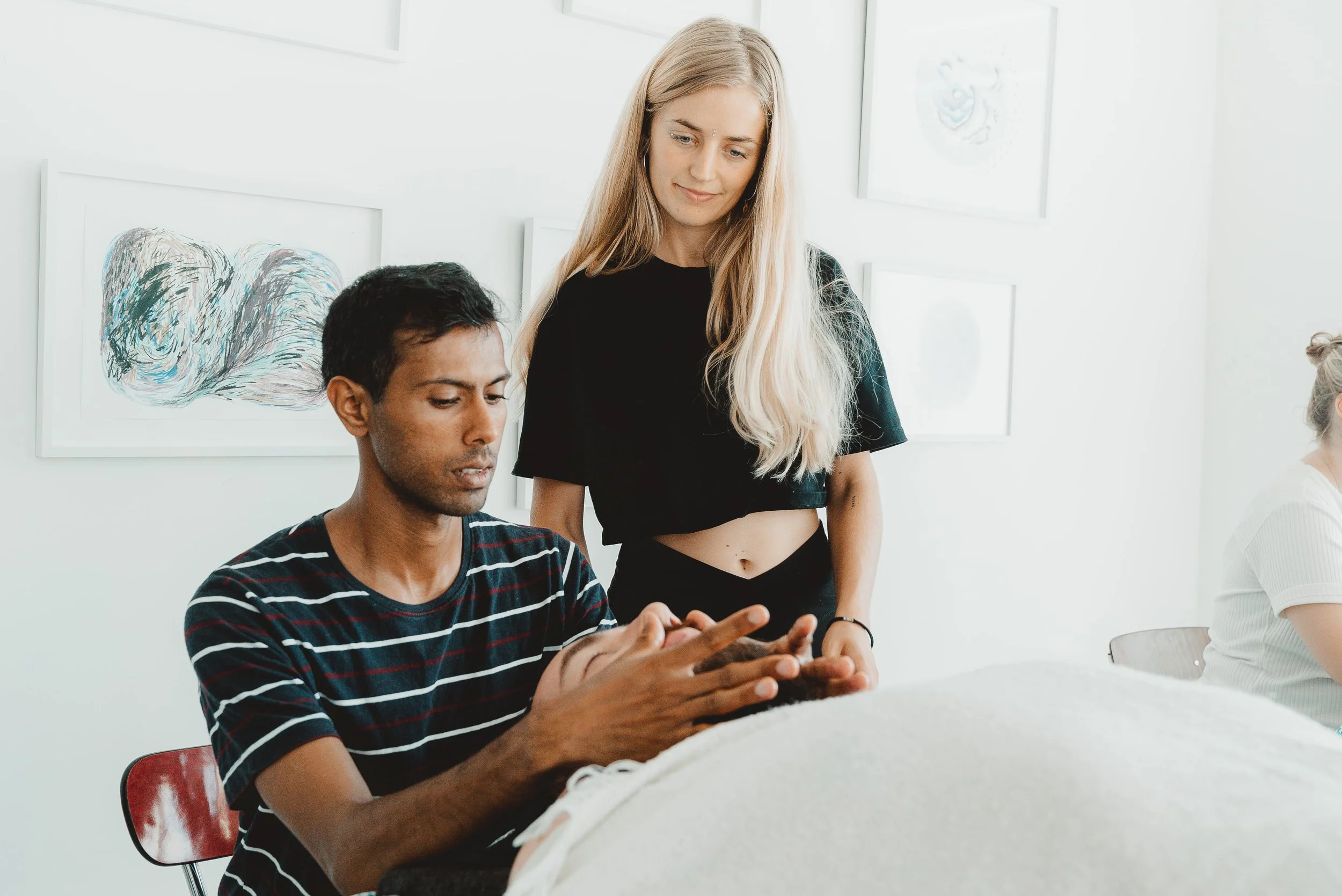 Woman looking at a man massaging another man smiling