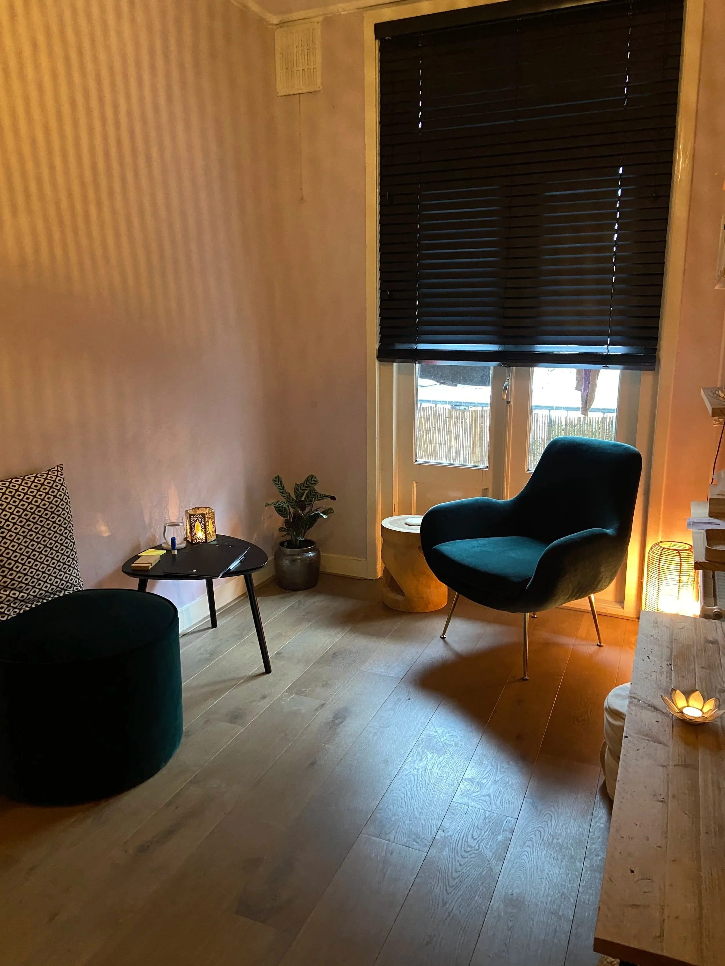 a talk therapy space with two green chairs, a table and some candles on the side