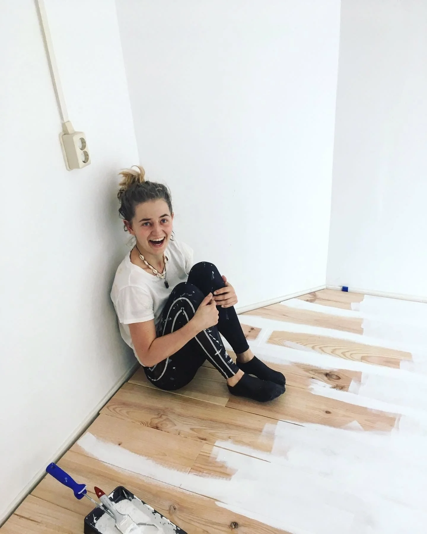 Woman who is sitting on floor with paint all around her looking scared