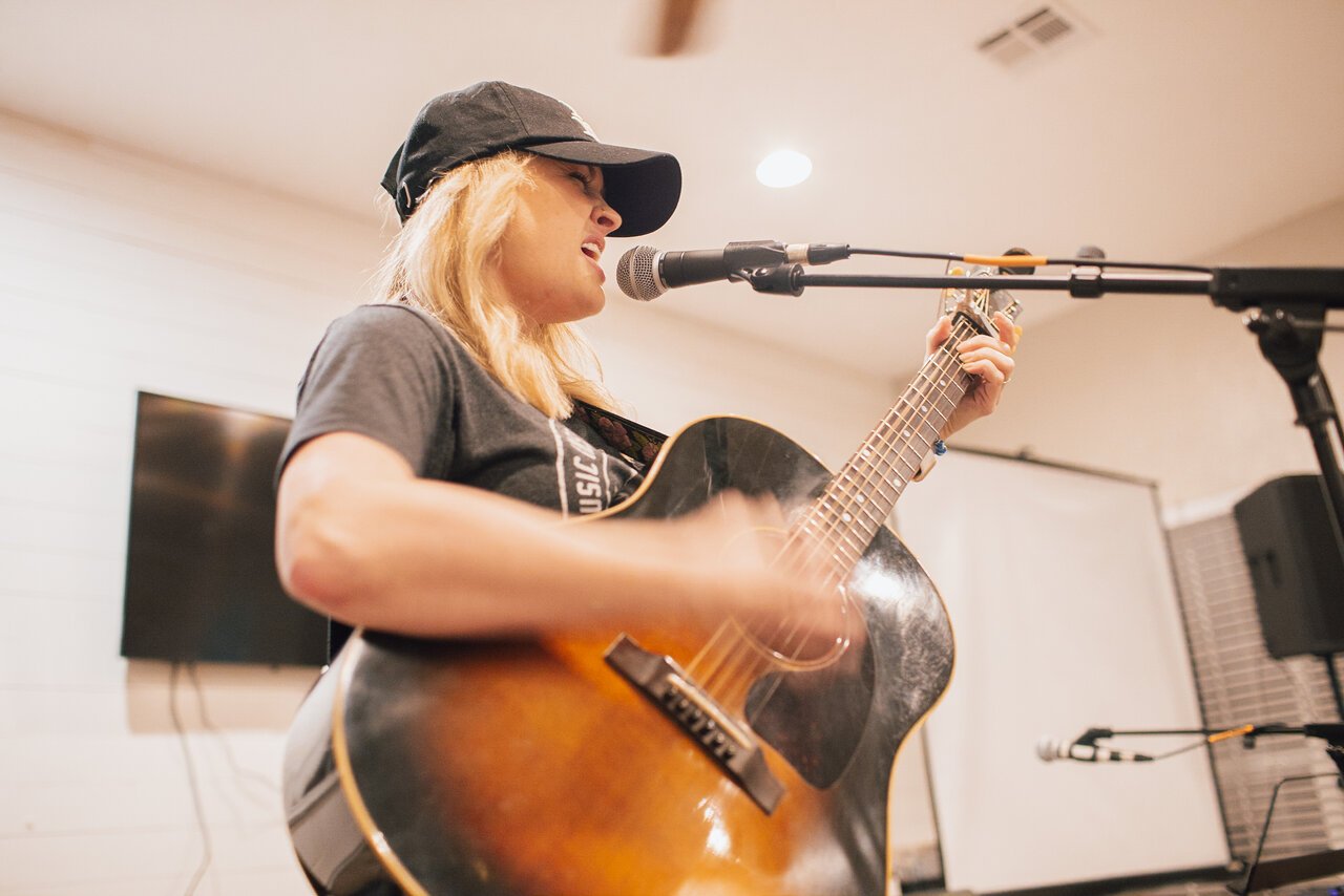 Guitar player & singer standing and performing in front of microphone