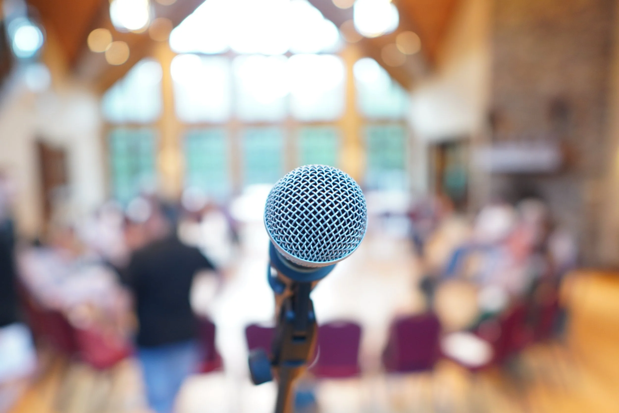 Zoomed in picture of a microphone, blurred background of people playing music