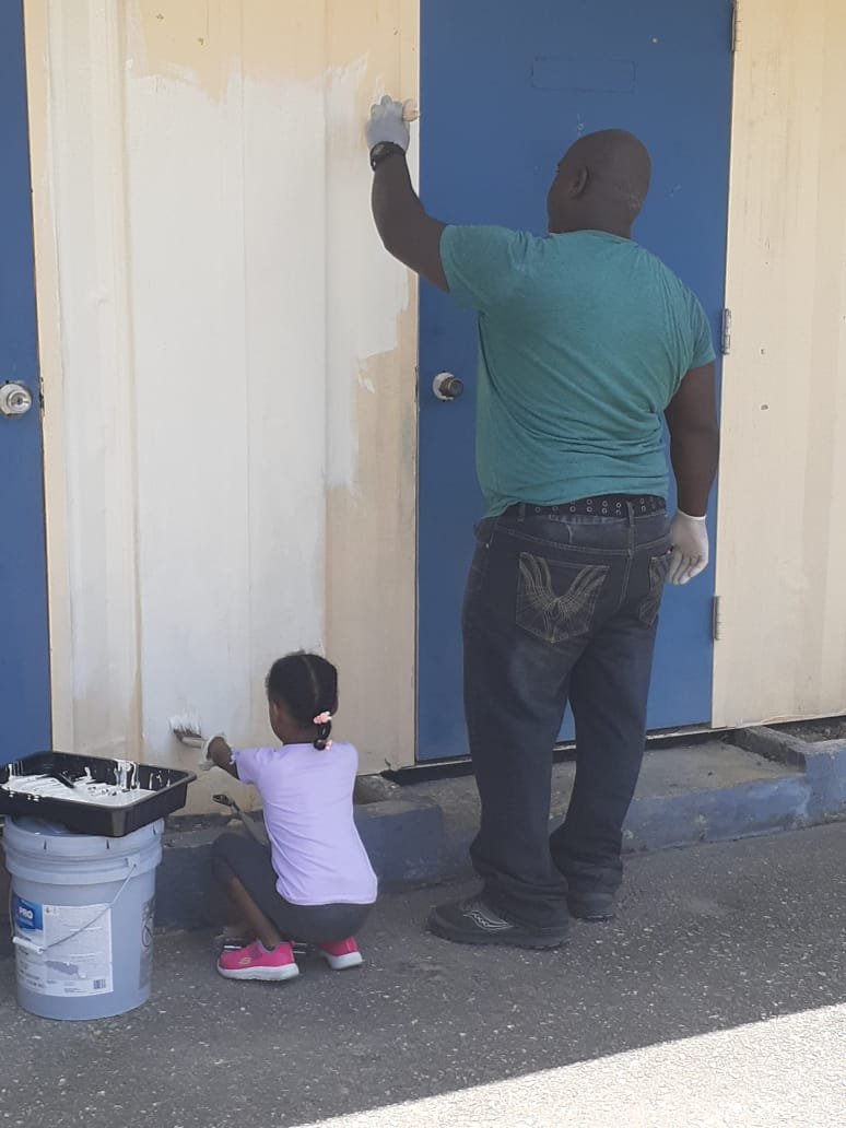 Our 5-year-old volunteer and her father painting.jpeg