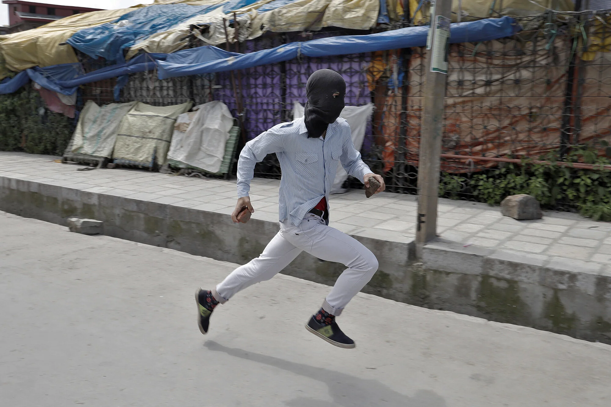 A stone pelter runs towards security forces during disturbances in Srinagar, Kashmir, 2017.